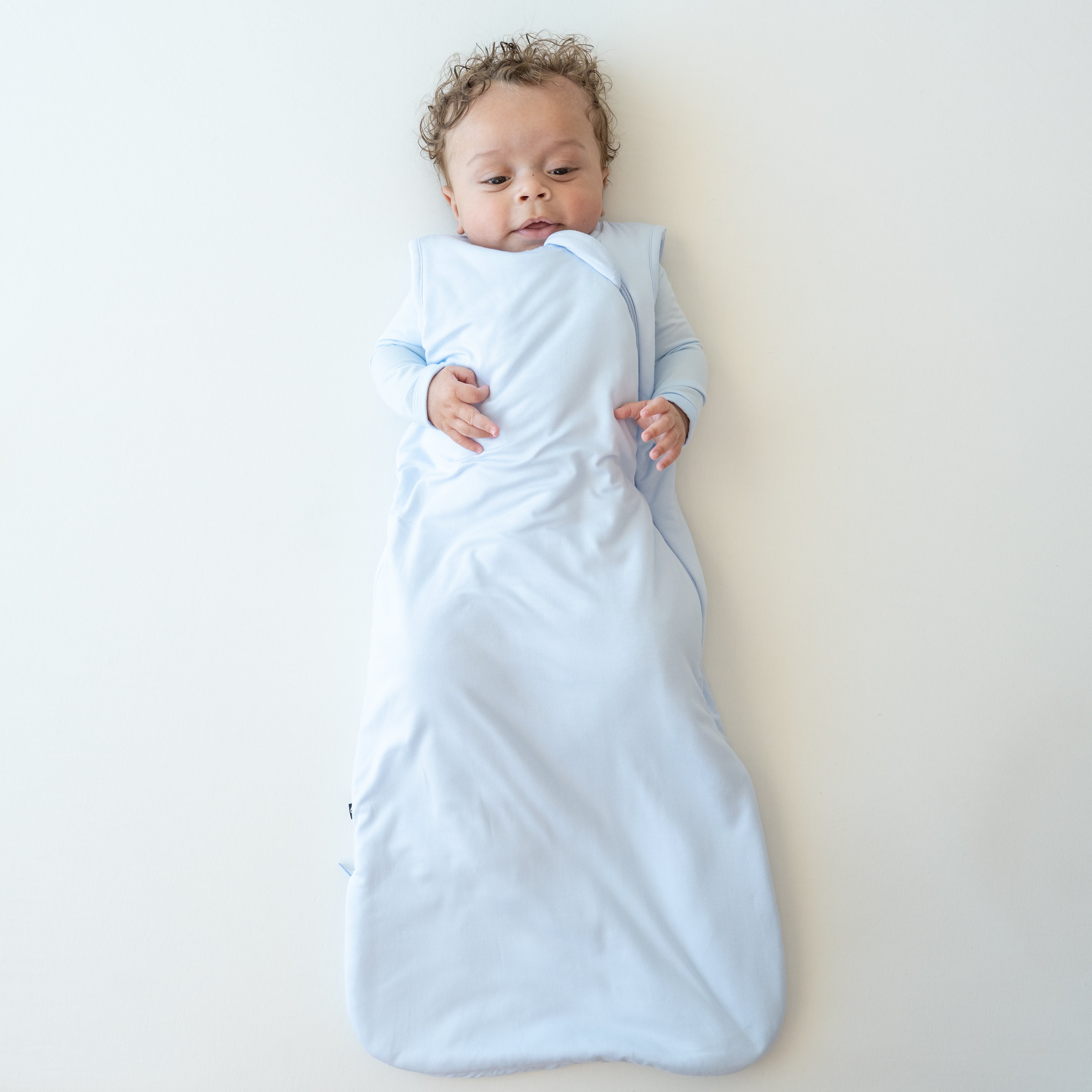 Infant wearing Sleep Bag in Mist 1.0 with matching romper underneath