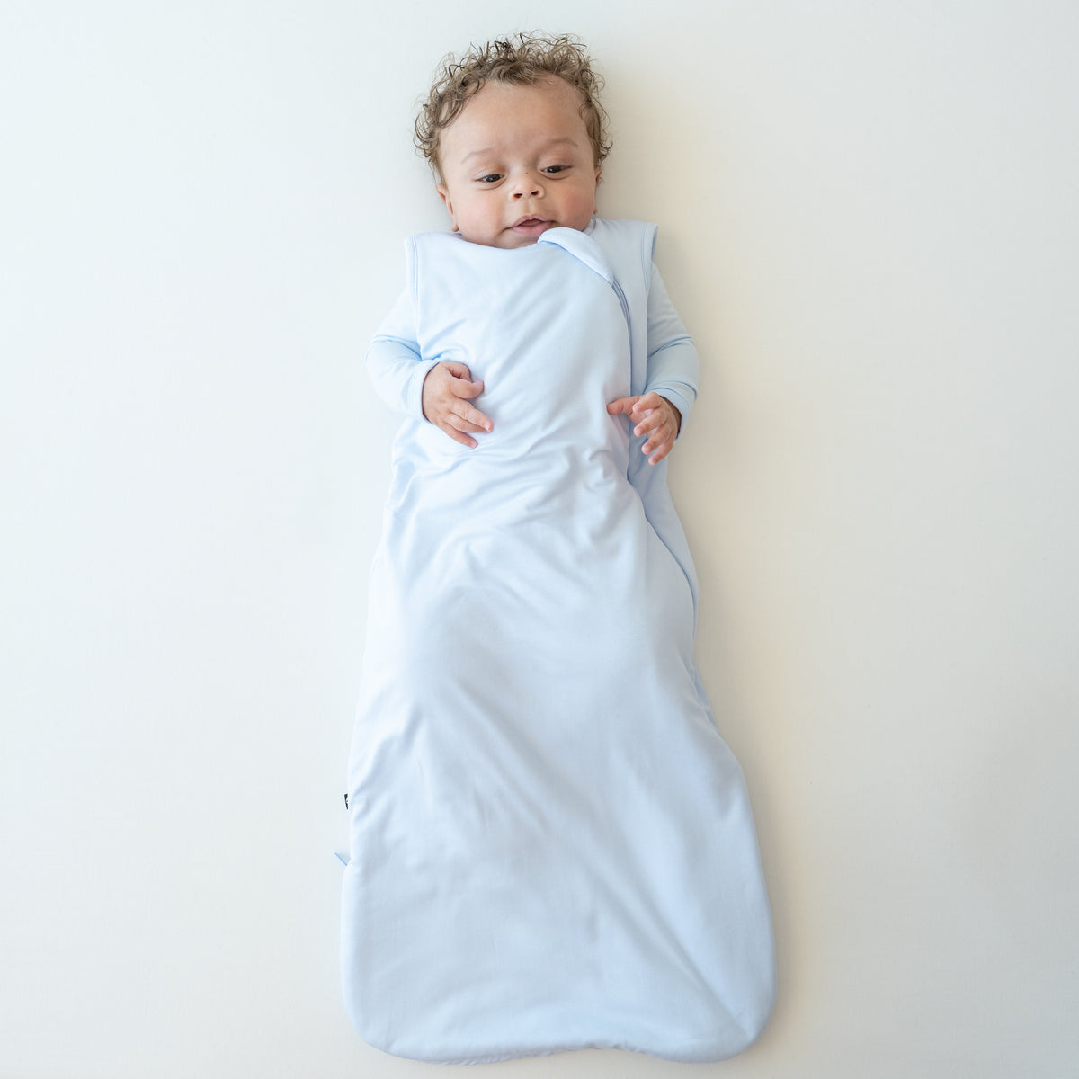 Infant wearing Sleep Bag in Mist 1.0 with matching romper underneath