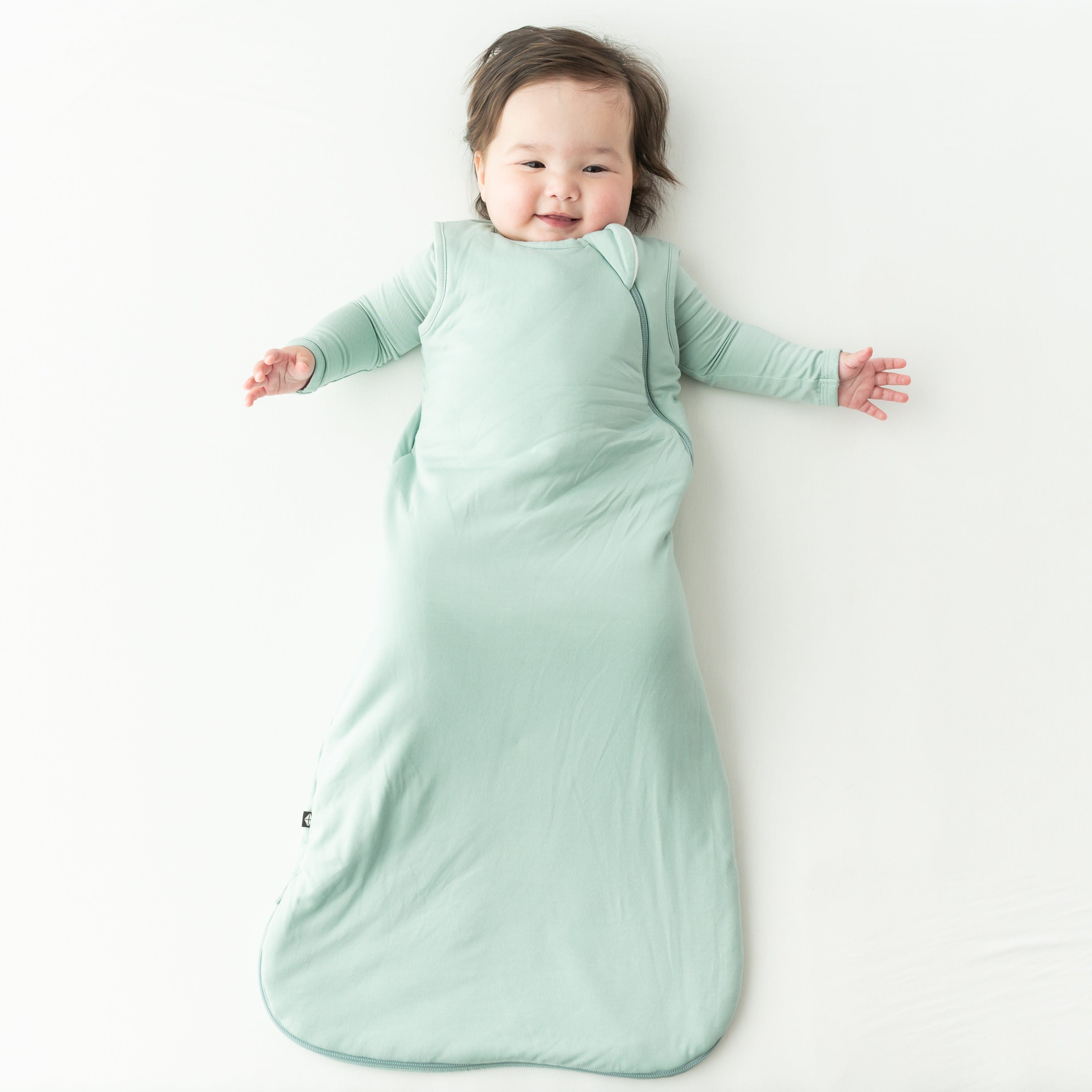 Baby in a light green buttery soft bamboo sleep bag on a white background