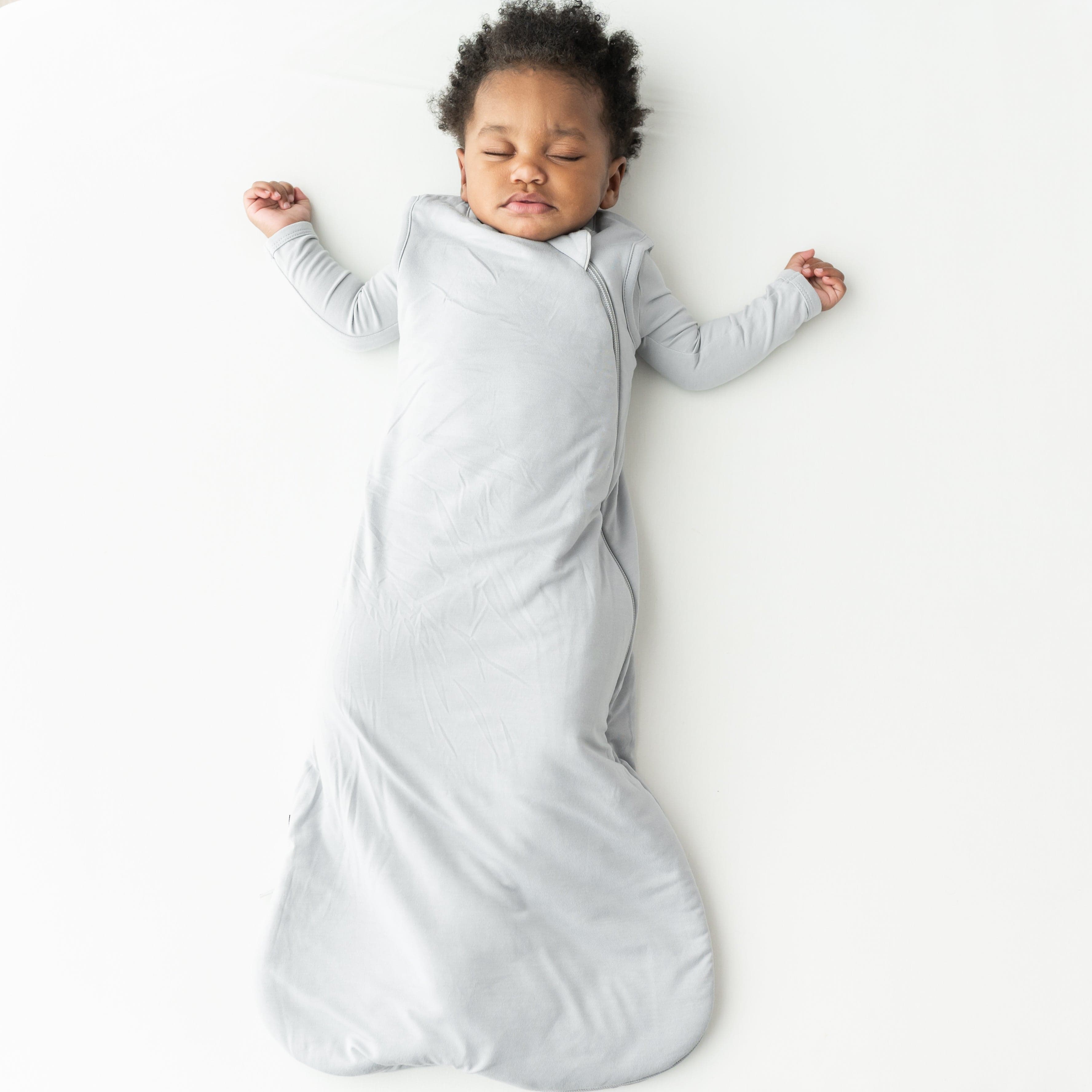 Child sleeping in a gray soft bamboo wearable blanket on a white background