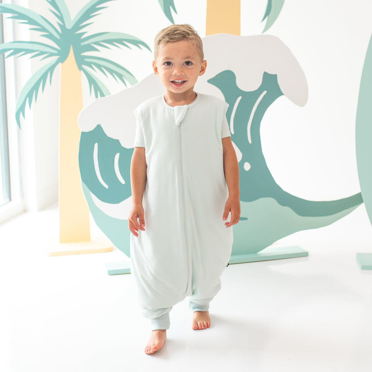 Young child model walking wearing the Sleep Bag Walker in Dew 1.0