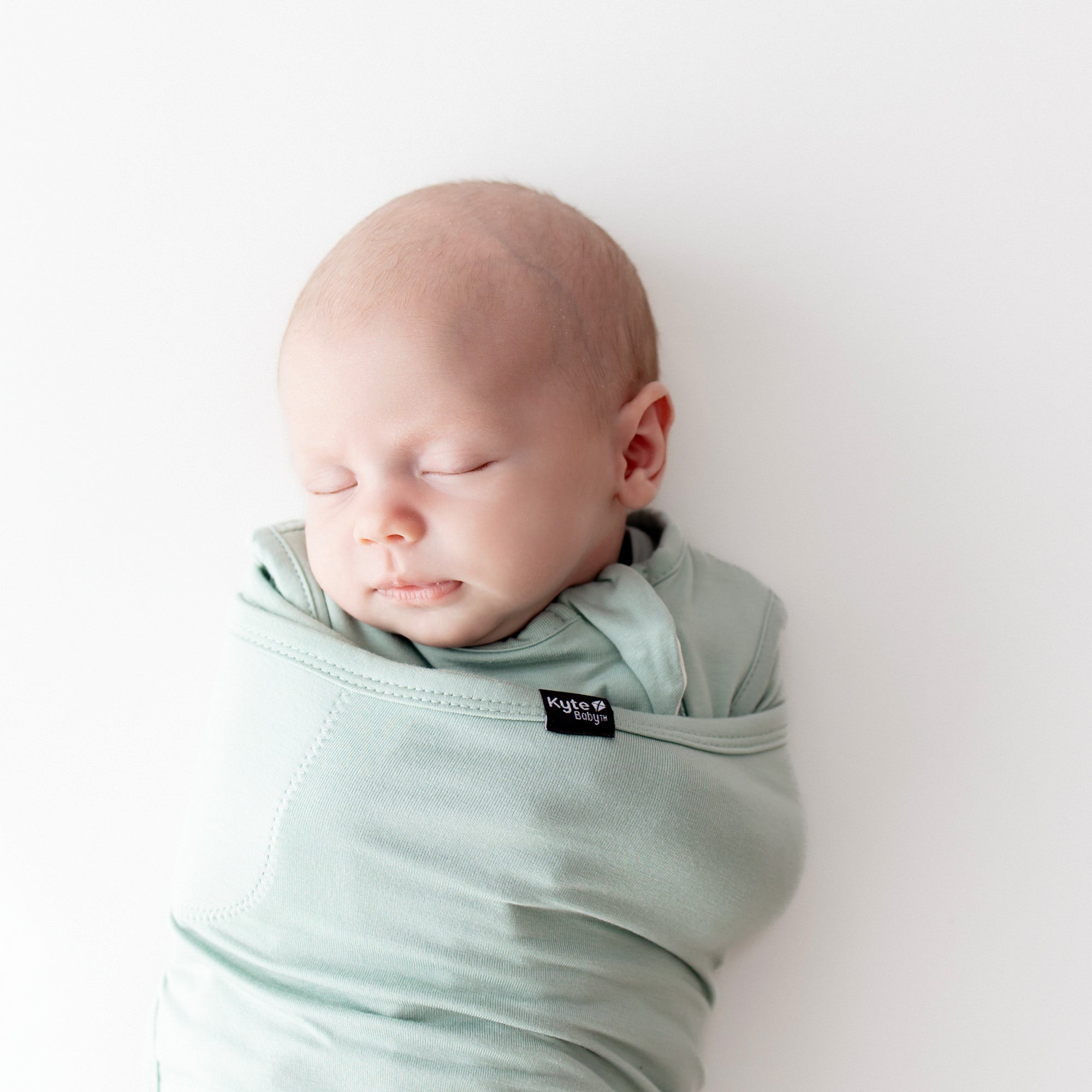 Baby sleeping swaddled in Sleep Bag Swaddler in Sage 0.5 close up