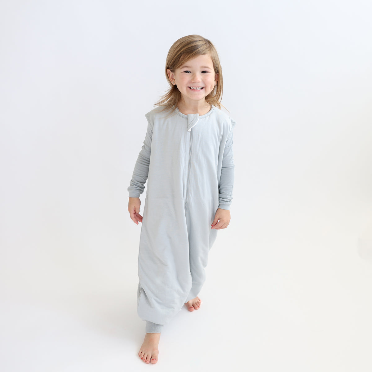 Child wearing a light grey sleep bag walker and matching grey pajama set