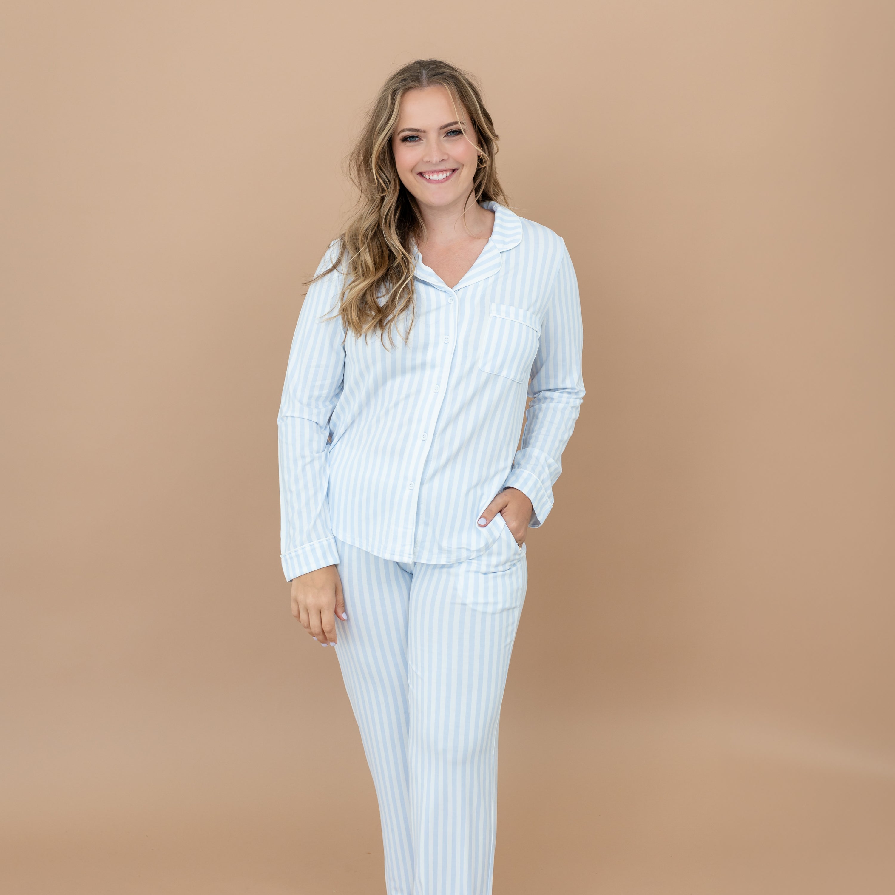 Close up of smiling model wearing the Long-Sleeved Women's Pajama Set in Small Mist Stripe with one hand in pants pocket