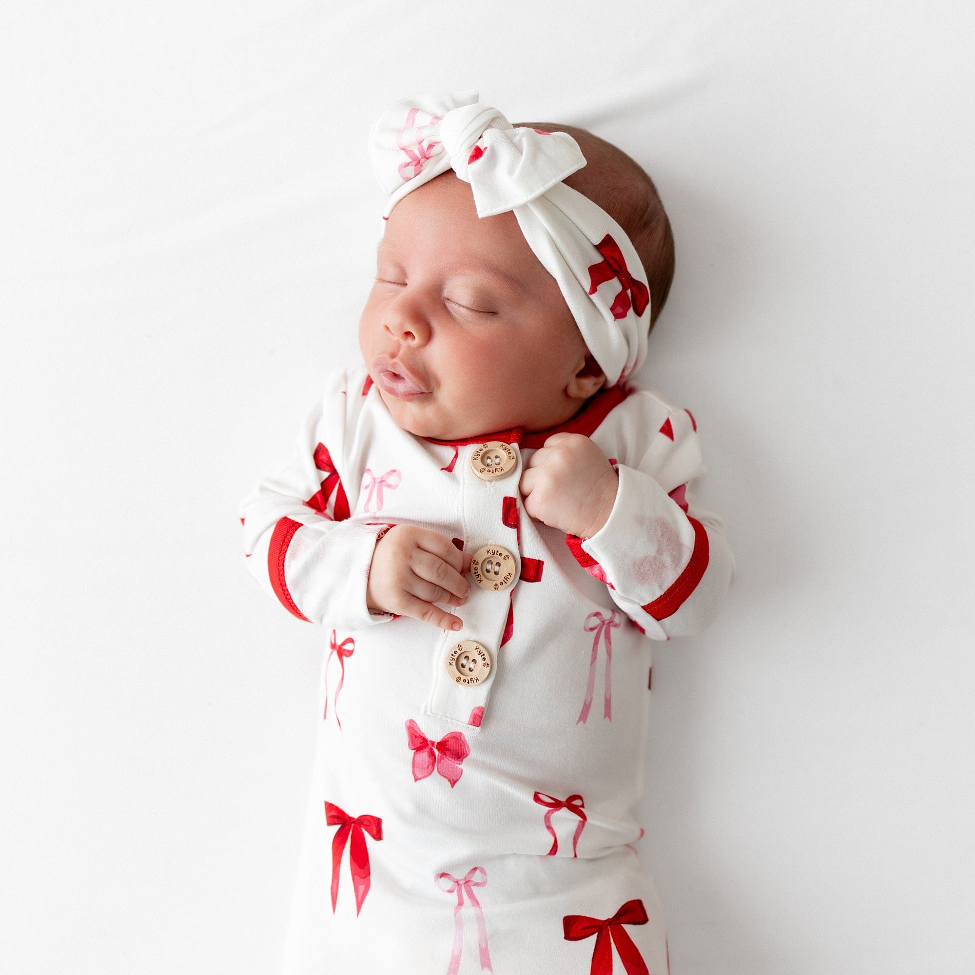 Close up of sleeping newborn wearing the Knotted Gown with Bow Set in Small Love Bow