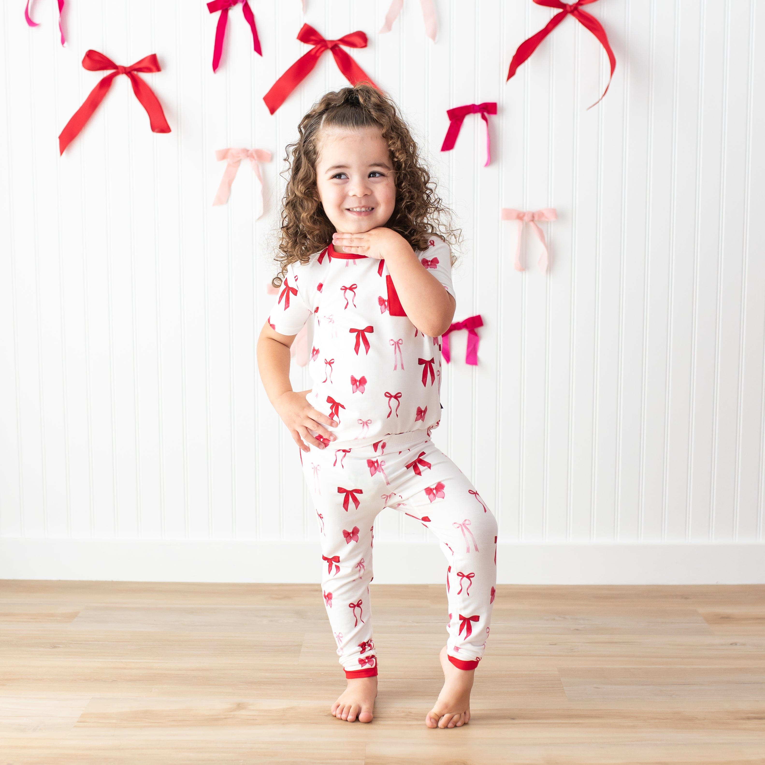 Young girl posting wearing the temperature regulating Short Sleeve with Pants Pajamas in Small Love Bow in front of a white paneled wall