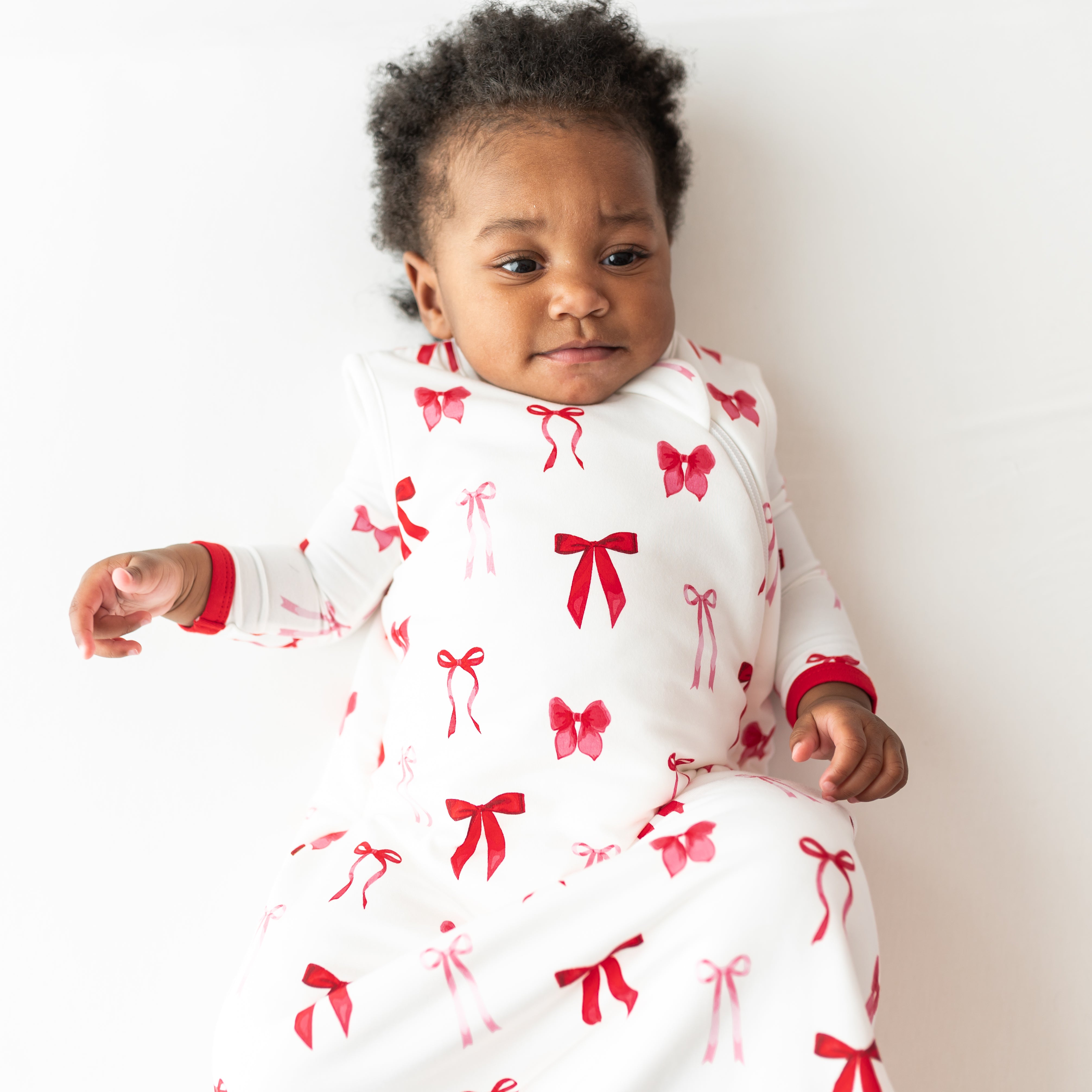Close up of young toddler wearing the Sleep Bag in Small Love Bow 1.0 with a matching romper on underneath