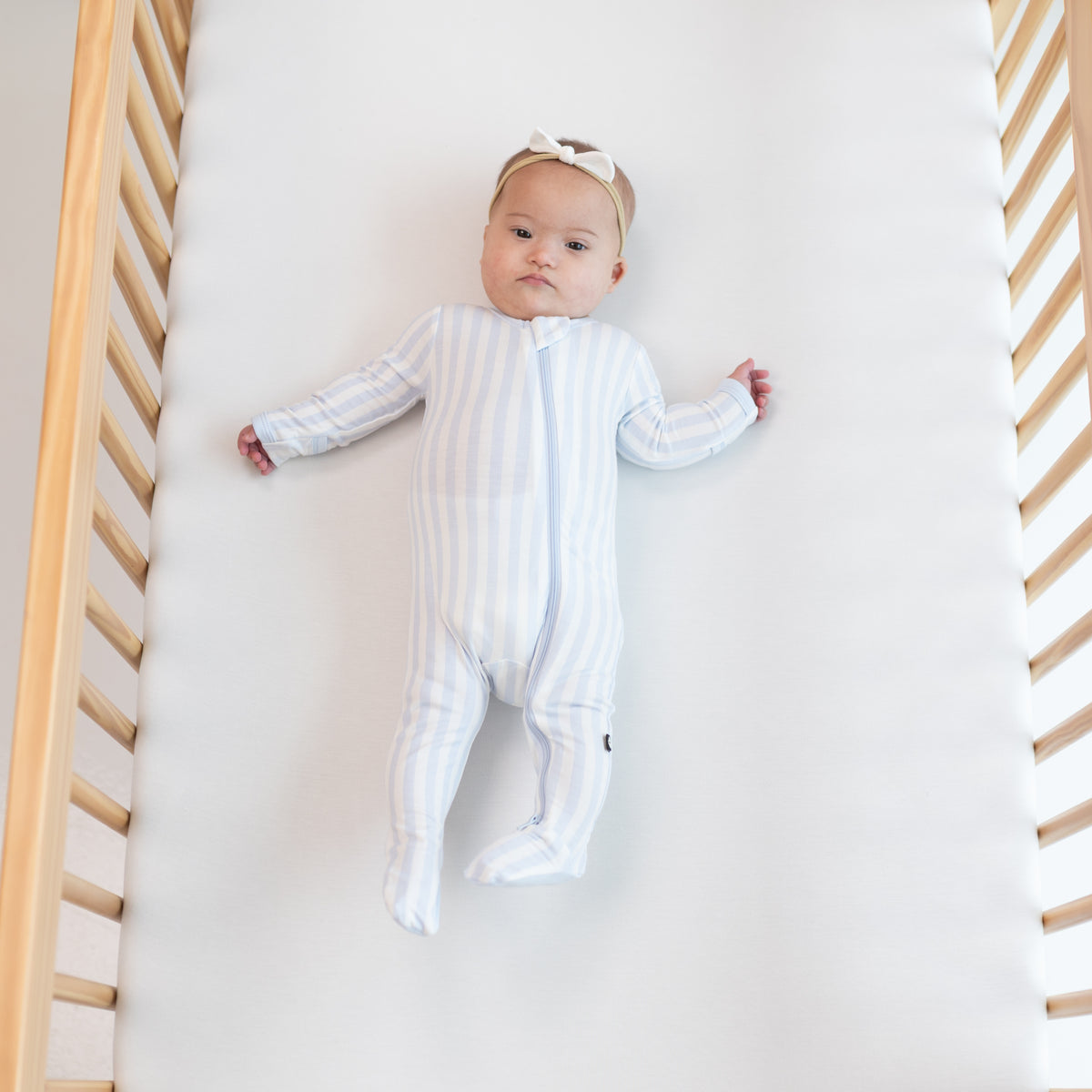 Infant wearing Zippered Footie in Small Mist Stripe with Tiny Nylon Bow in Cloud