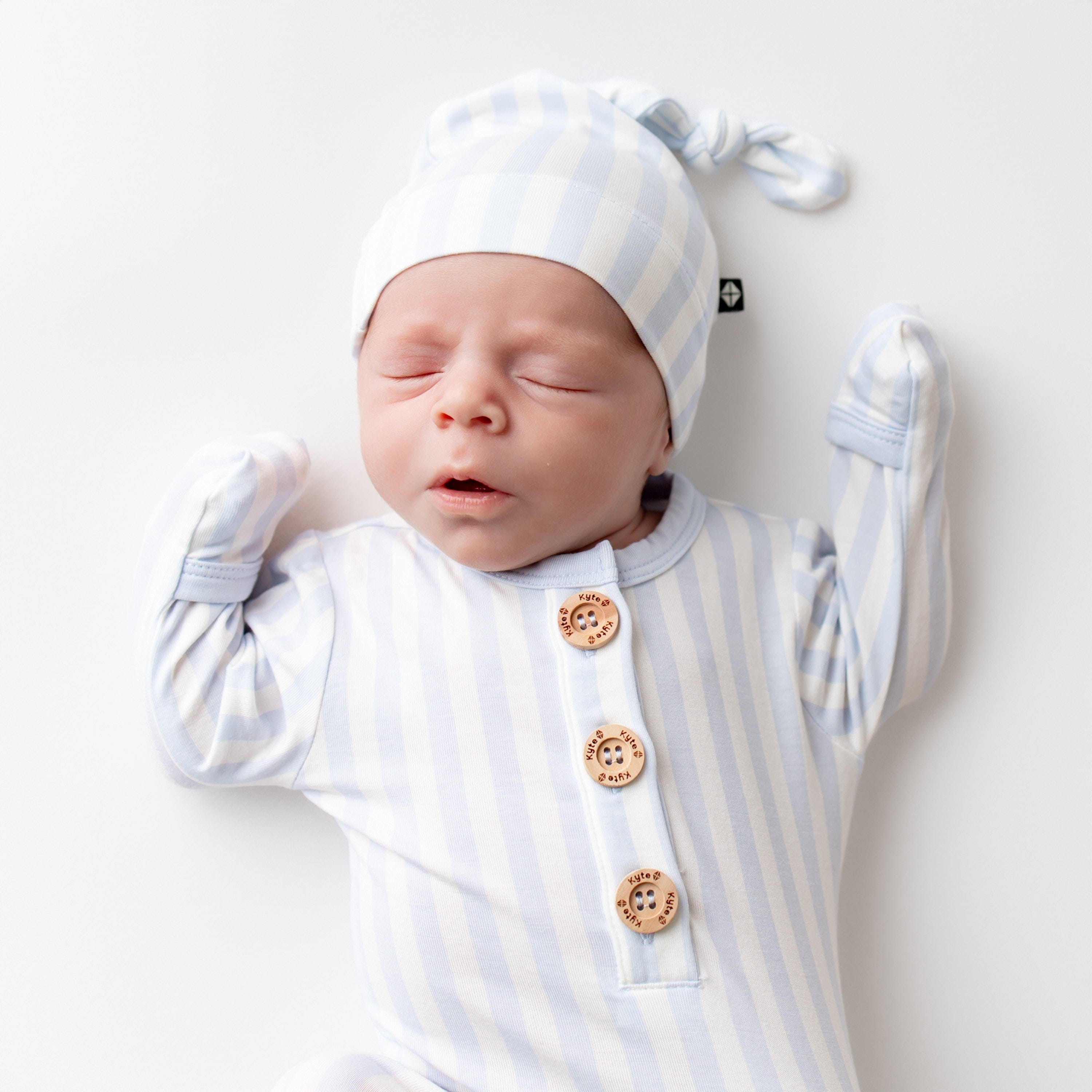 Close up of sleeping infant wearing the Knotted Gown with Hat Set in Small Mist Stripe
