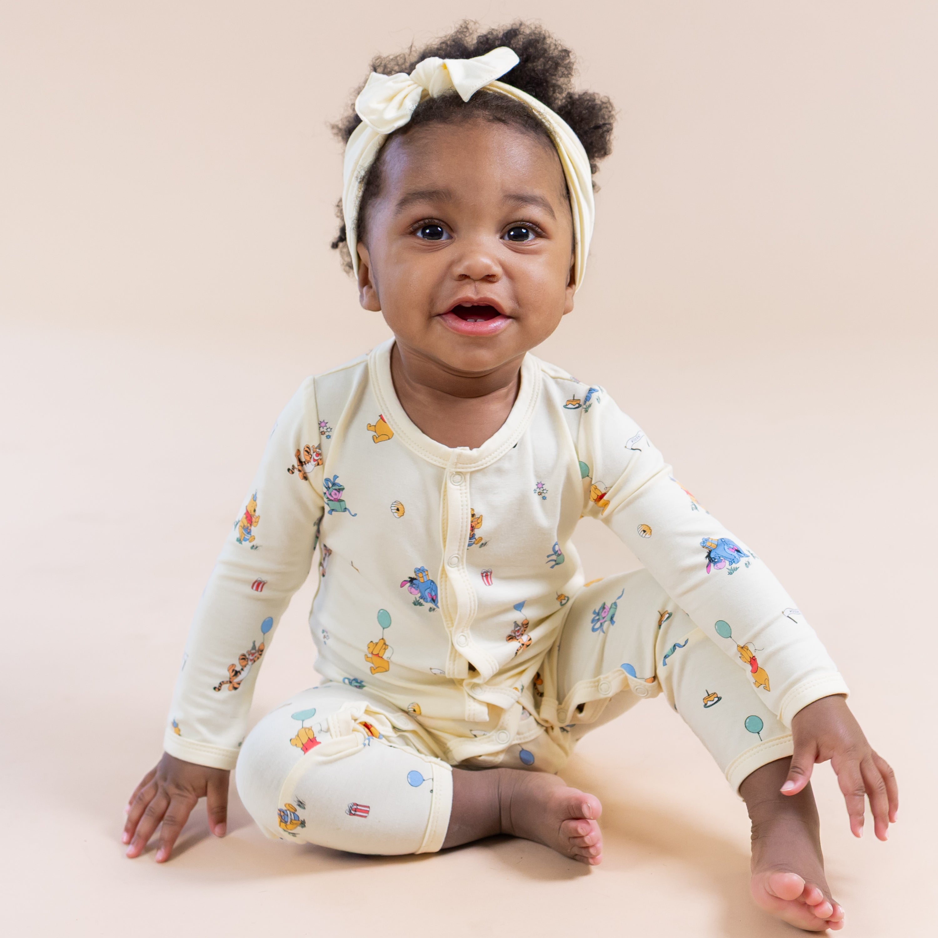 Young toddler sitting on the floor wearing the Romper in Winnie the Pooh Celebration