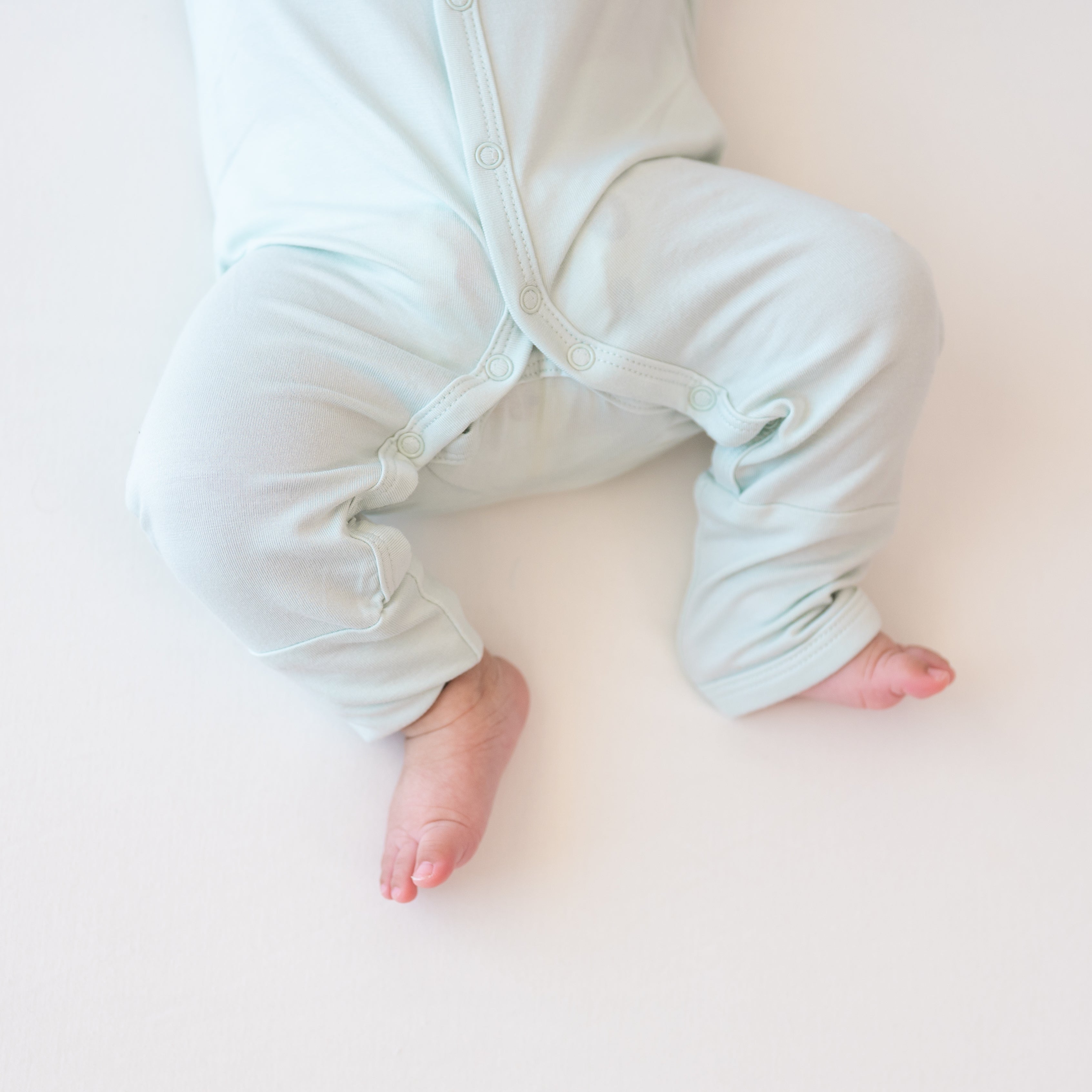 Close up of Romper in Dew snap closures on the legs while being worn on a baby