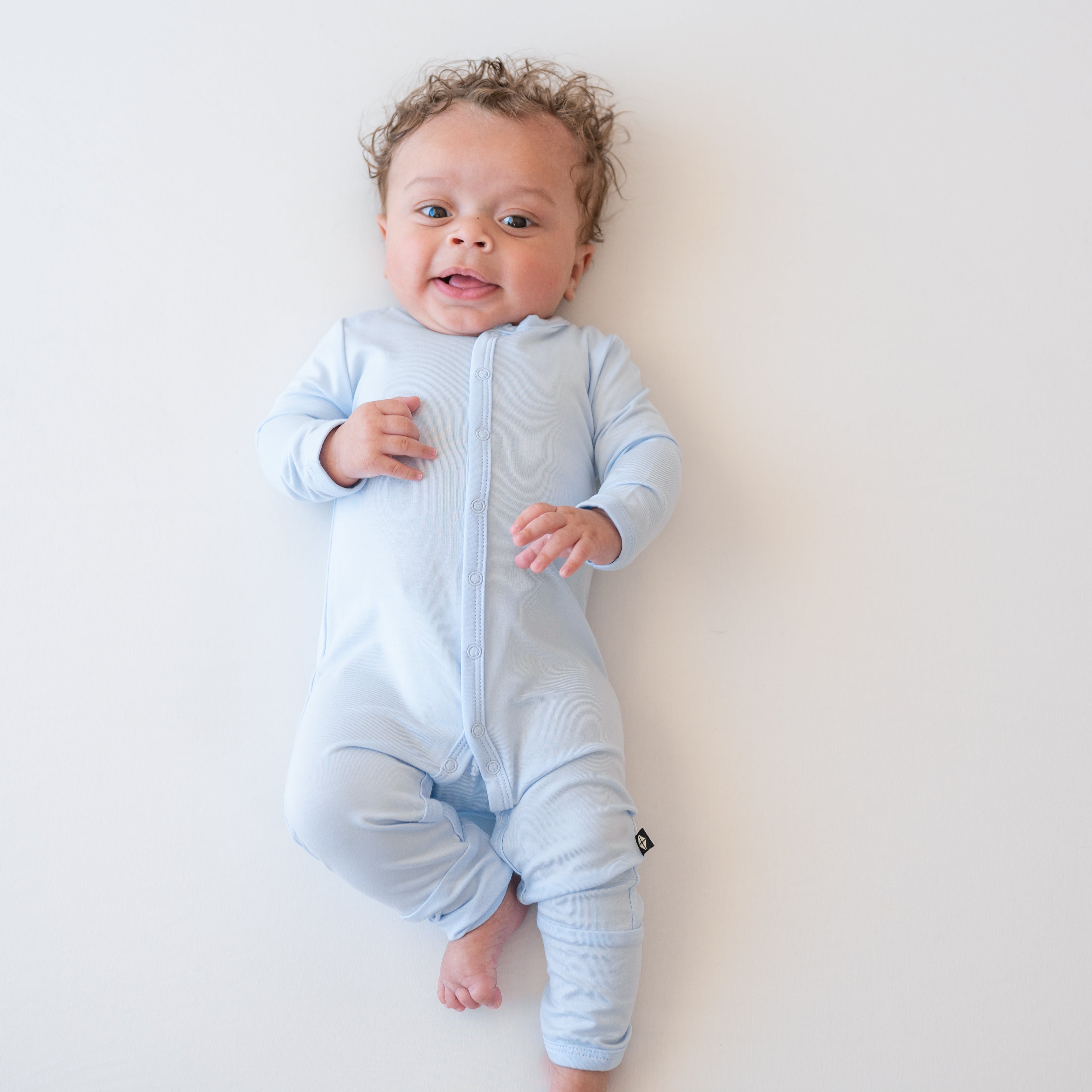 Infant model laying down wearing the Romper in Mist