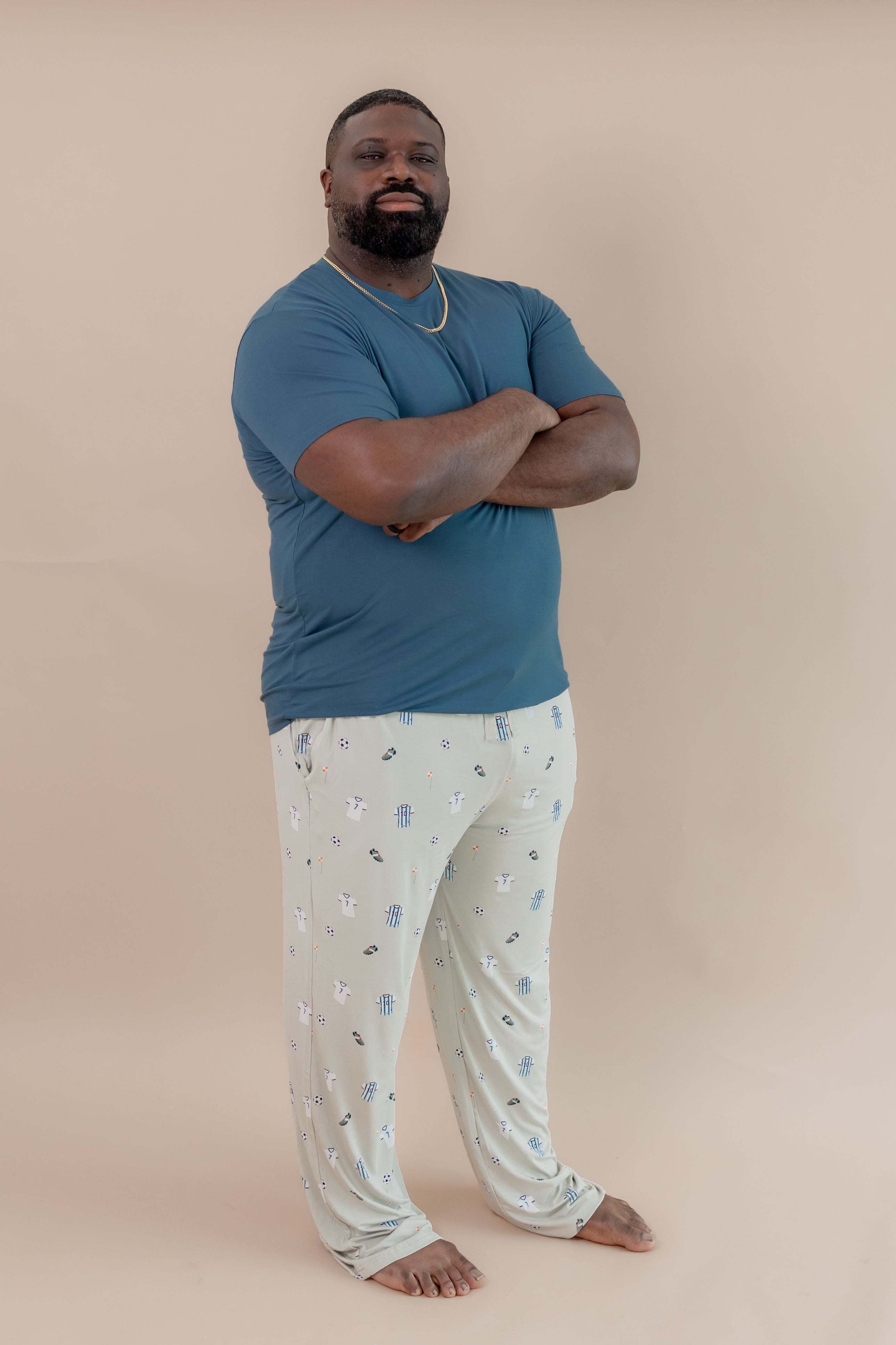 Man wearing Men's Lounge pant in Soccer print under an Atlantic T-shirt on a beige background