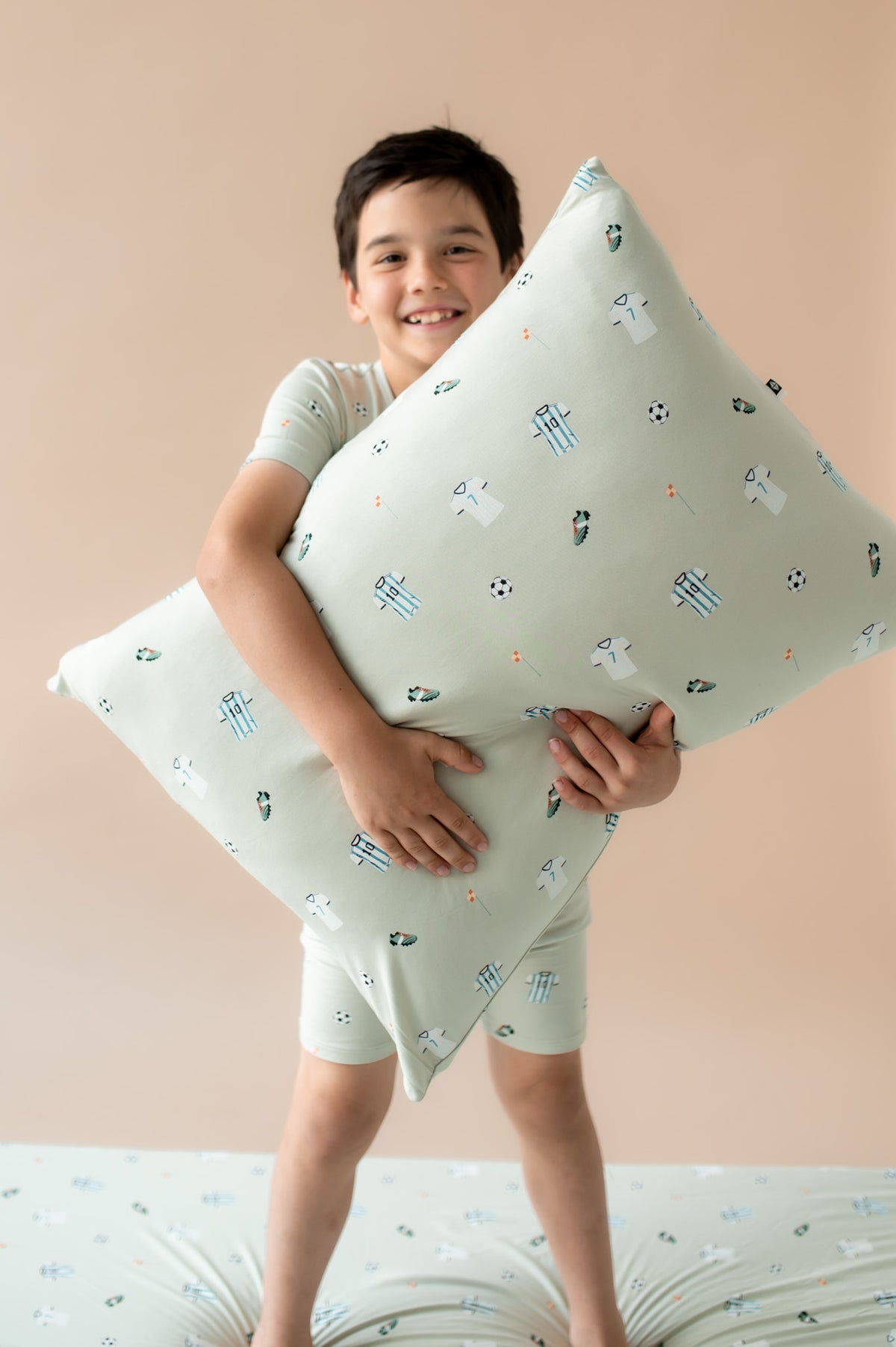 child holding a pillow with a soccer pattern
