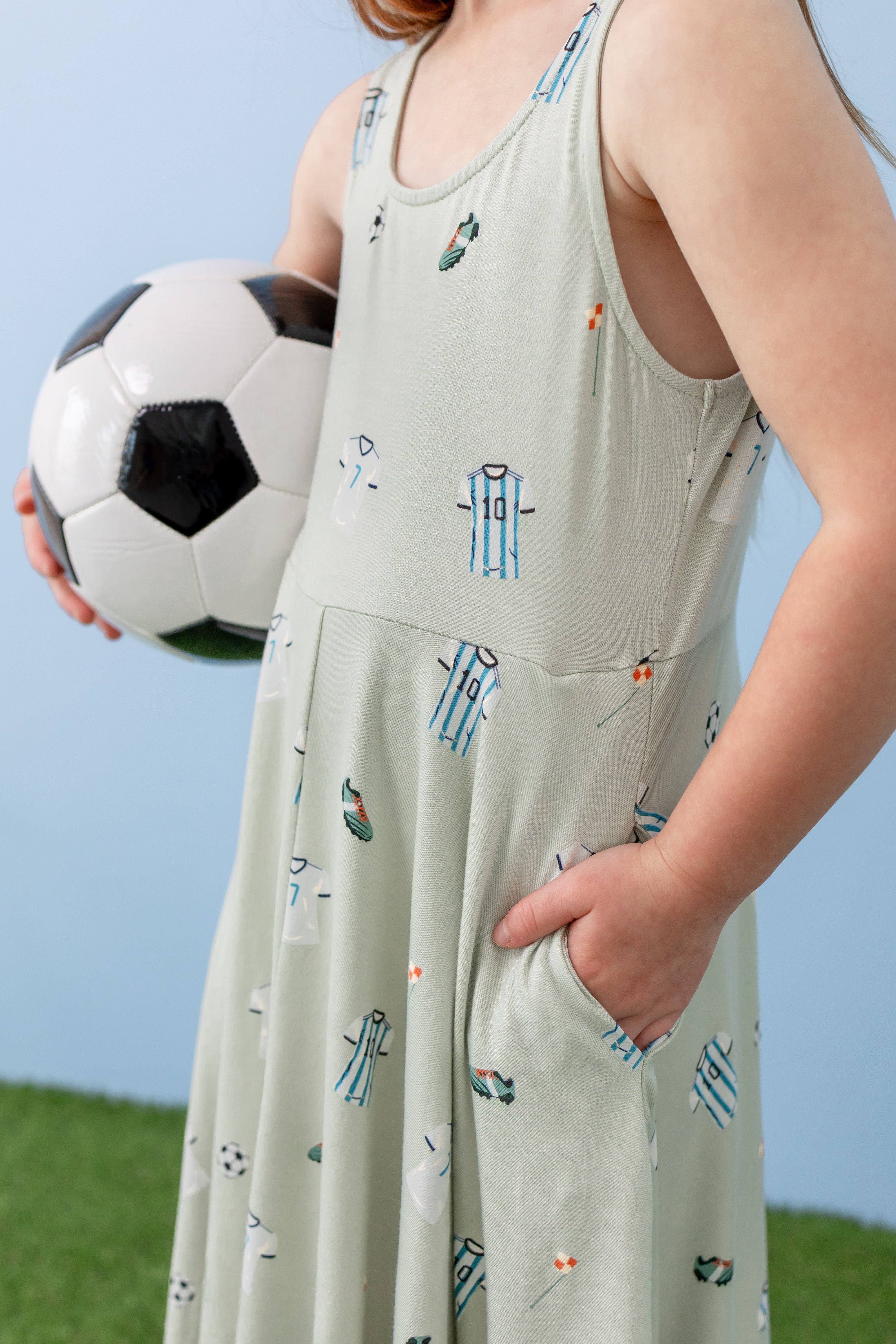Child wearing Tank Twirl dress with pockets in Soccer print holding a soccer ball