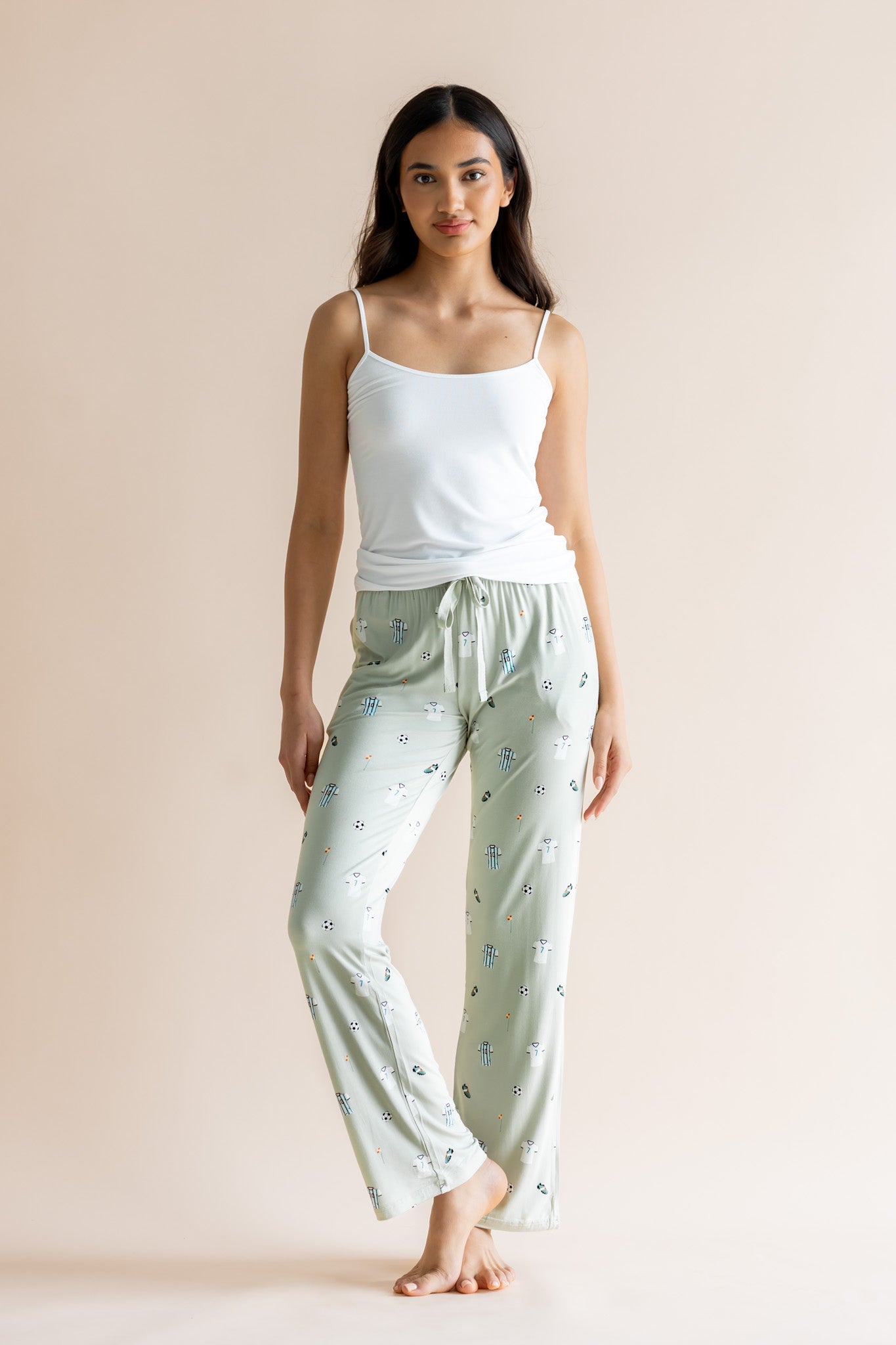 Model posing in Women's Lounge pant in Soccer print under white camisole on a beige background