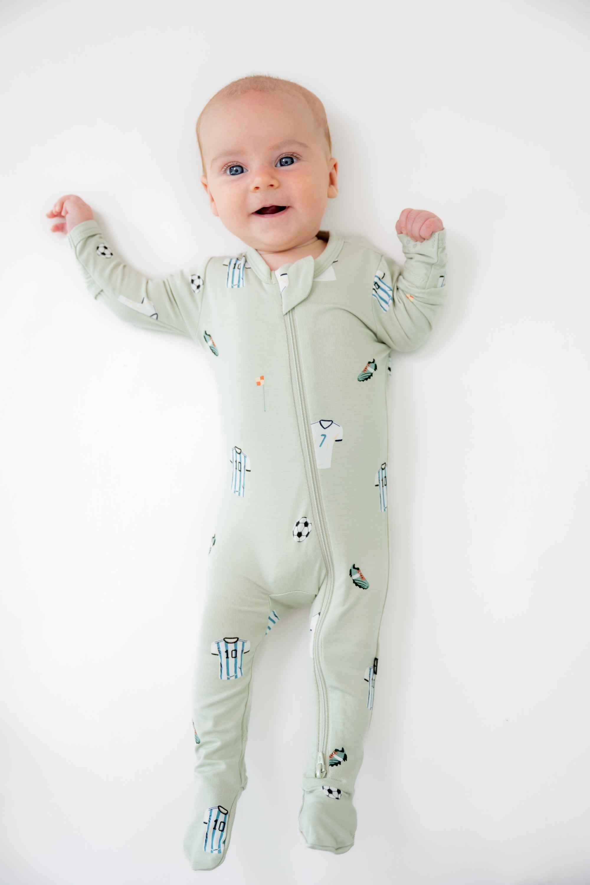Baby wearing Soccer print zippered footie on a white background