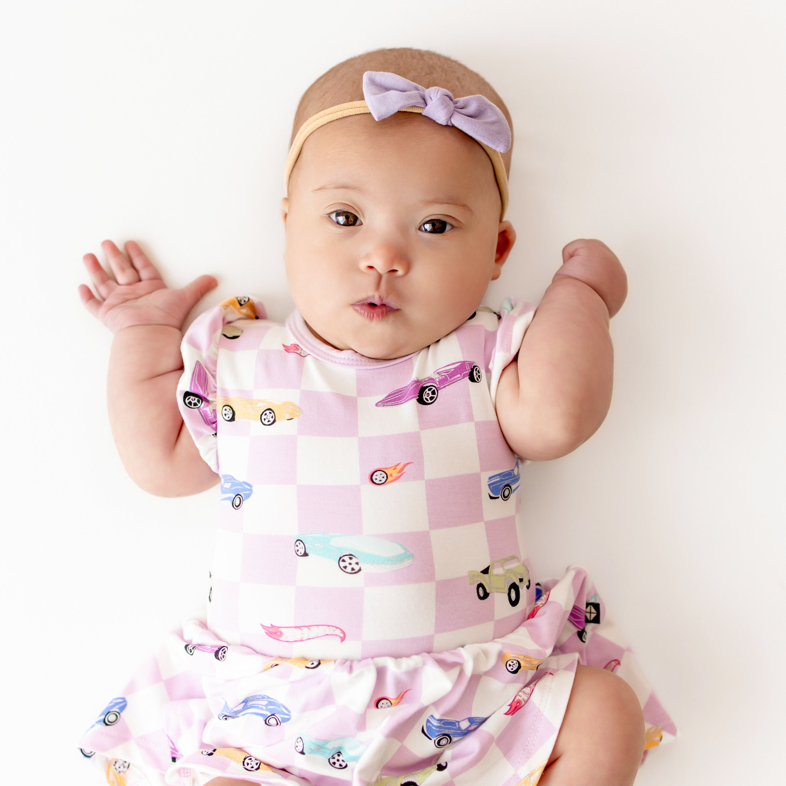 Close up of an infant wearing the Twirl Bodysuit Dress in Sparkles and Speed