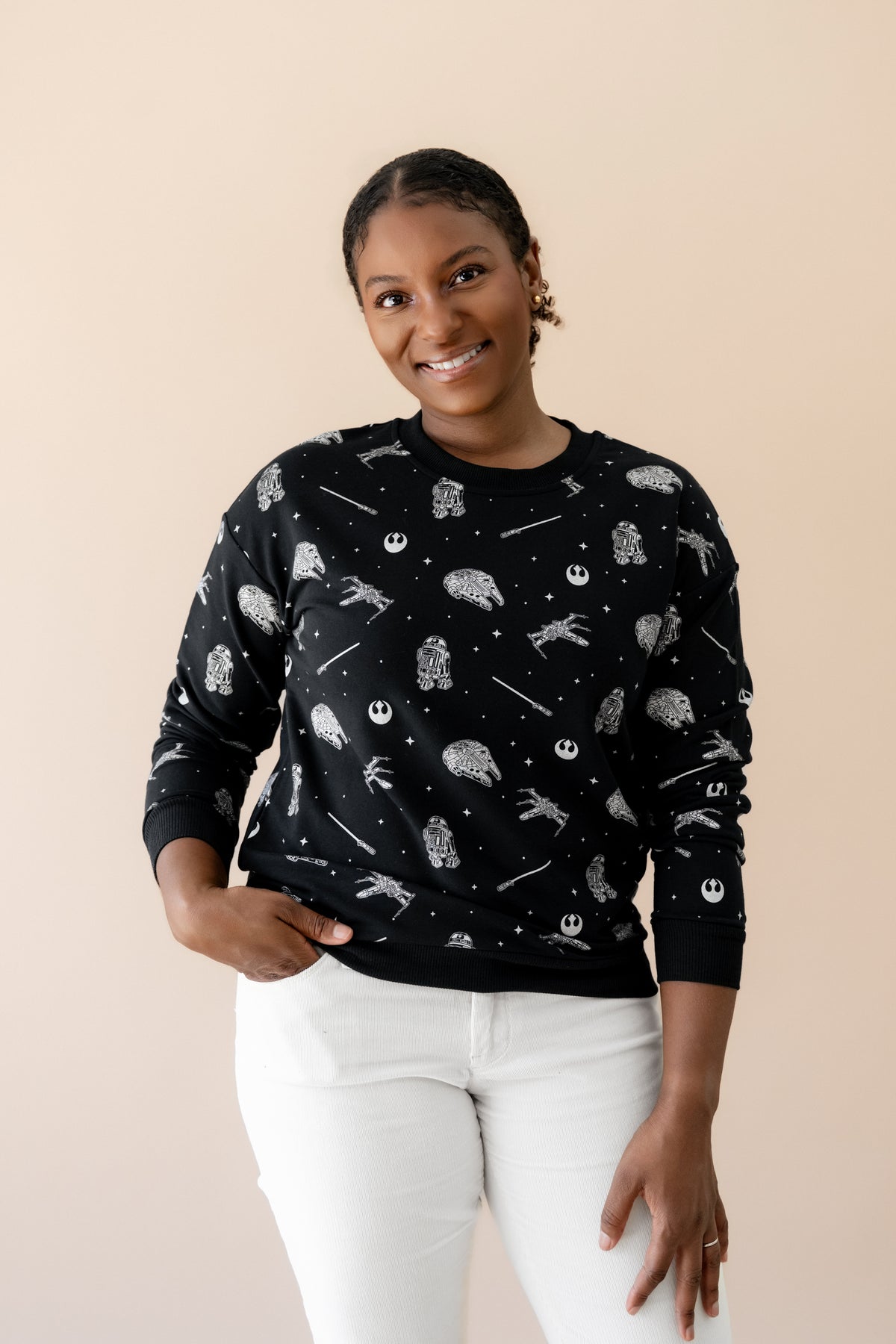 Smiling female wearing the Women's Sweatshirt in STAR WARS™ with cream colored pants