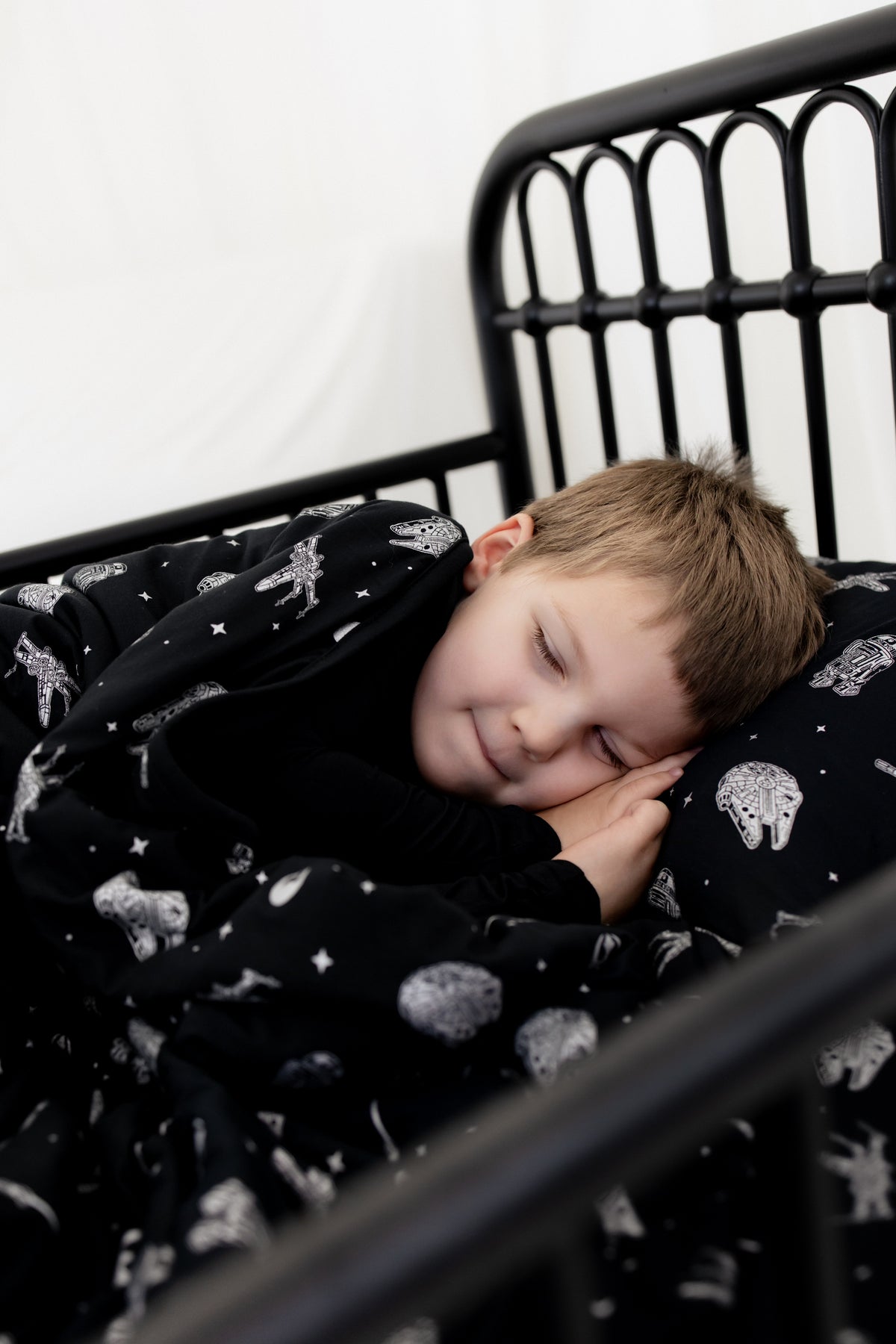 Boy sleeping in a bed laying on a pillow with the Toddler Pillowcase in STAR WARS™ on it