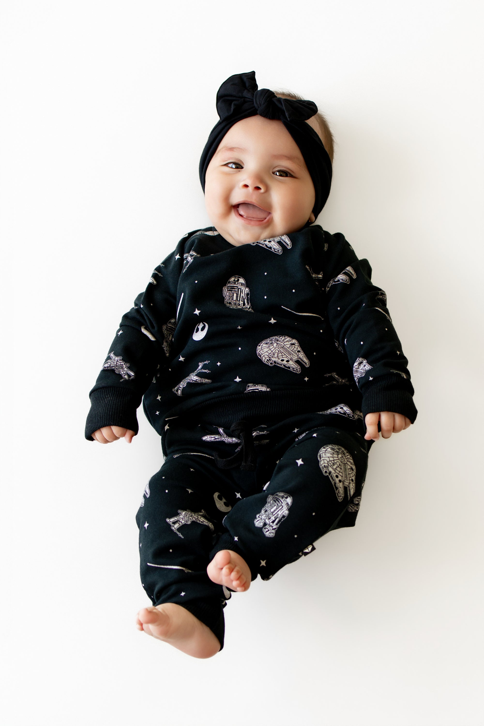 Smiling infant wearing the Long Sleeve Jogger Set in STAR WARS™ paired with a black bow