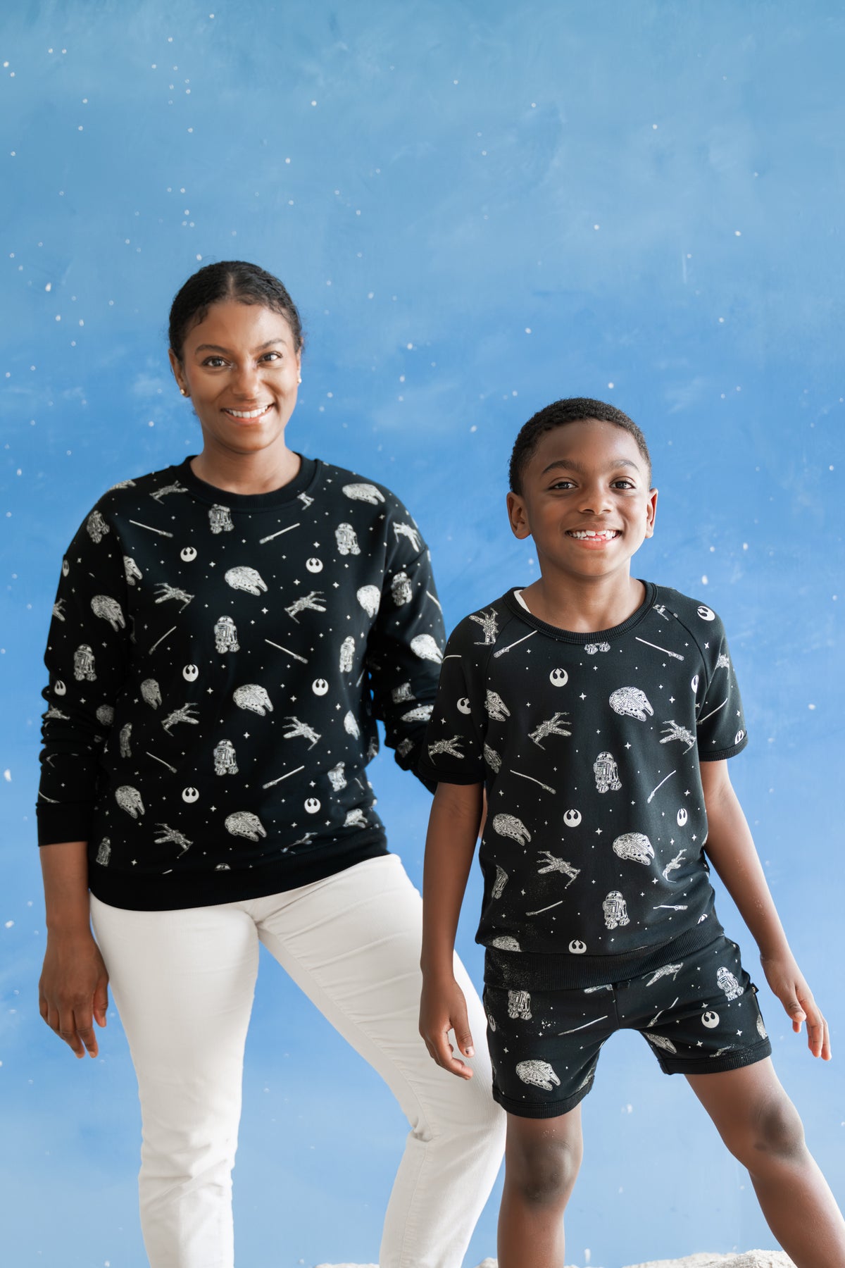 Female wearing the Women's Sweatshirt in STAR WARS™ standing beside her son who is wearing the matching short sleeve set