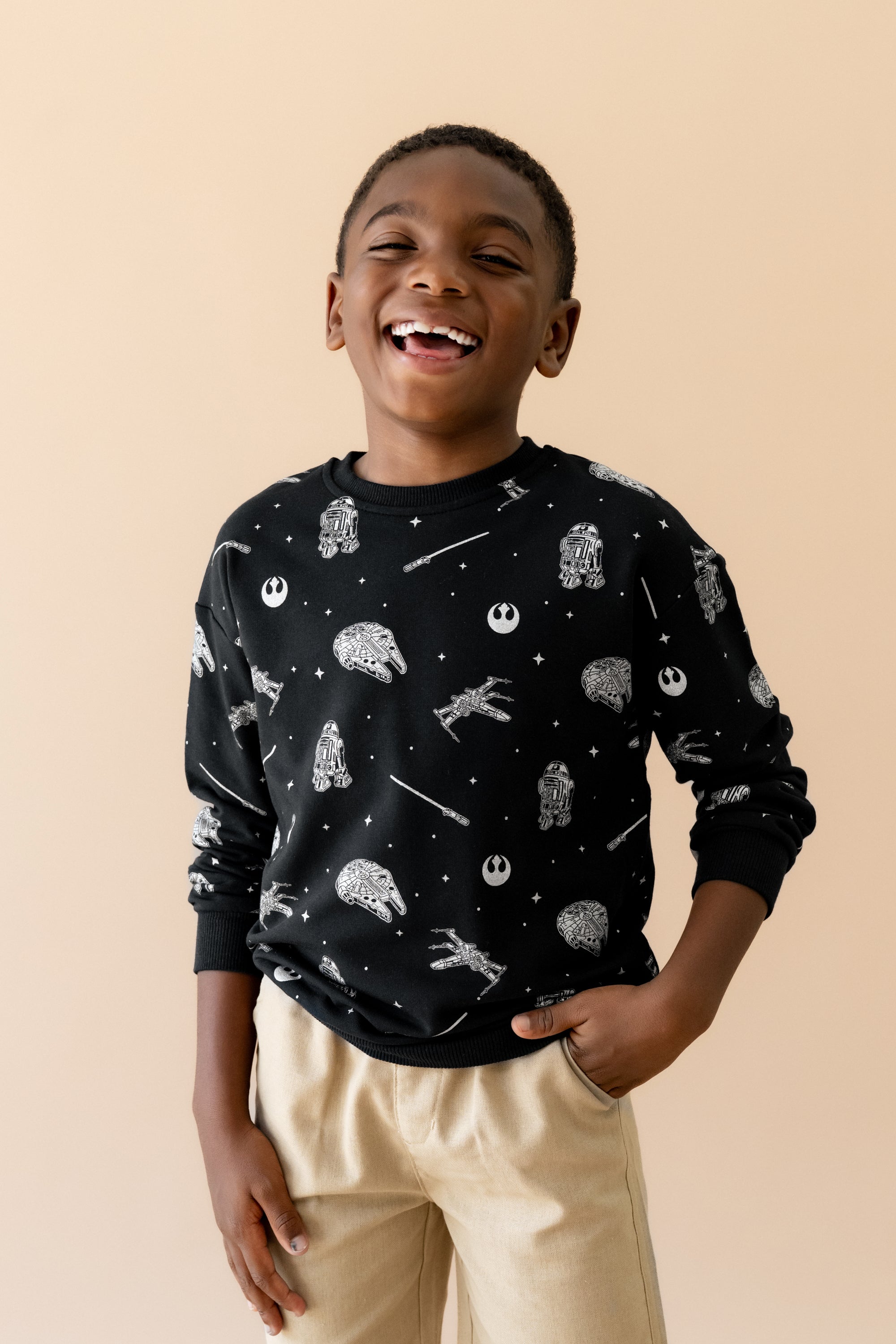 Smiling boy wearing the Sweatshirt in STAR WARS™ with tan shorts