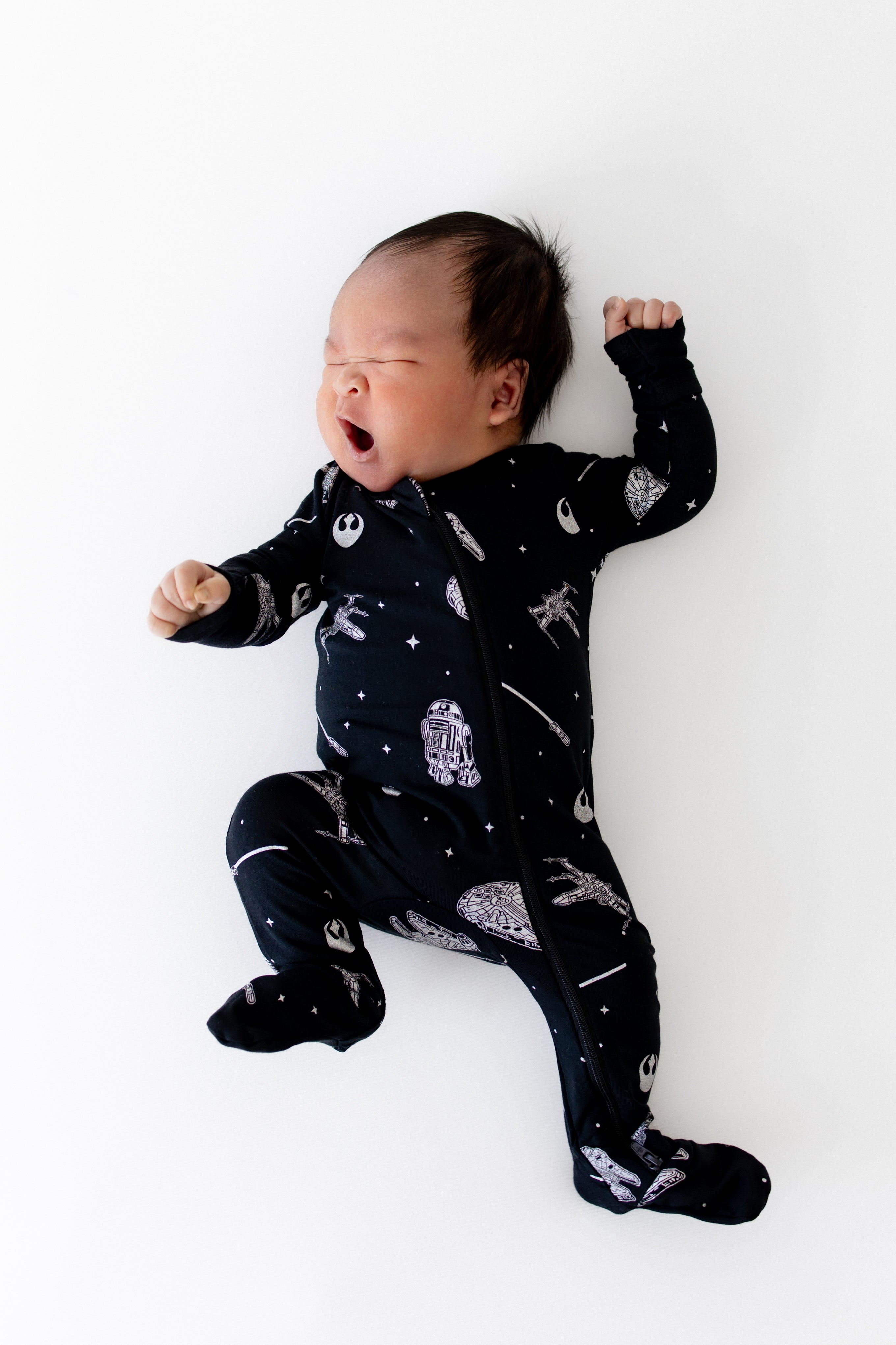 Newborn stretching out yawning wearing the Zippered Footie in STAR WARS™