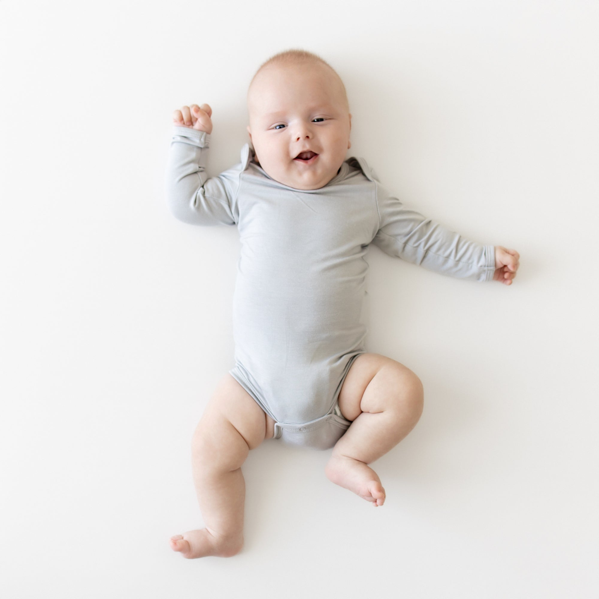 Baby wearing a gray onesie on a white background