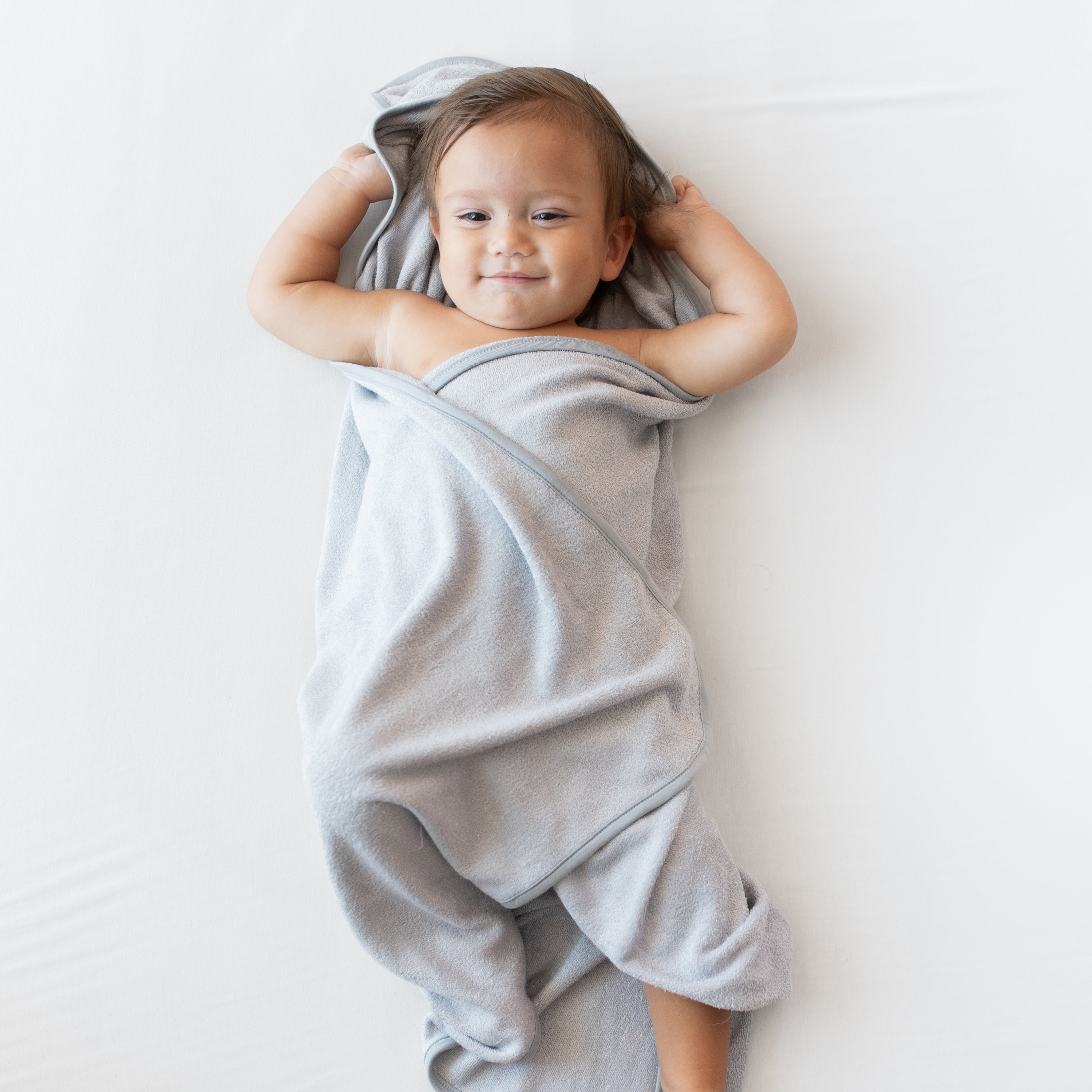 infant laying down wrapped in the Hooded Bath Towel in Storm