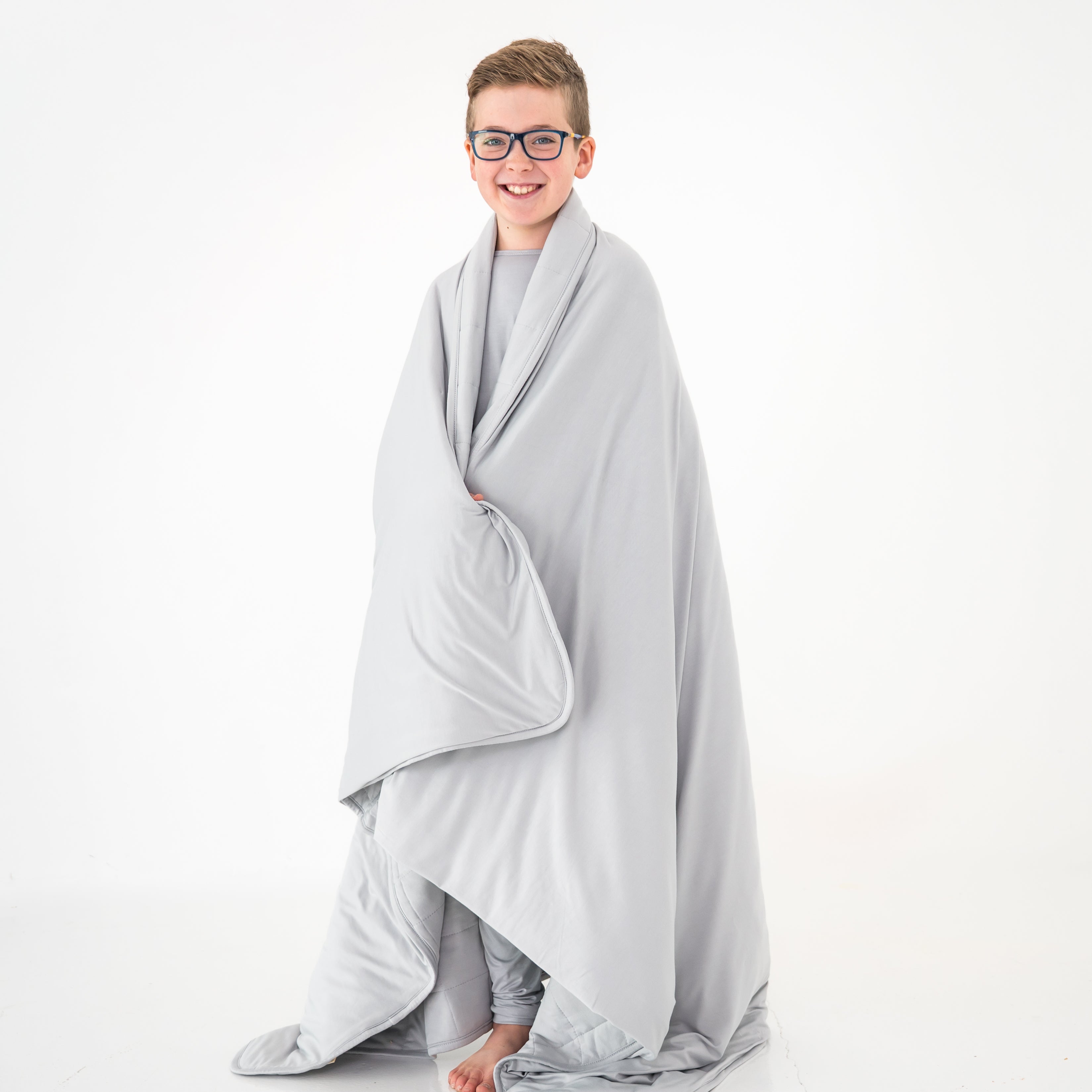 Child wrapped in a gray blanket on a white background