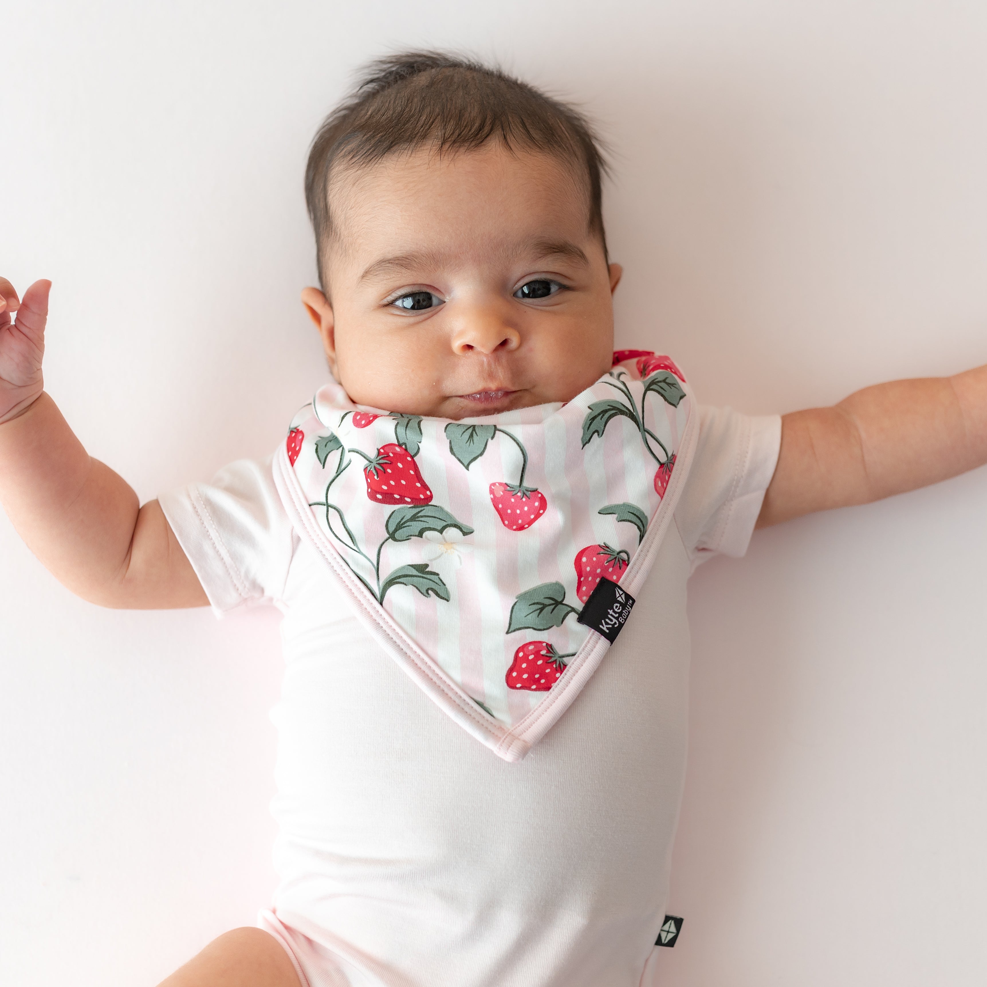 Infant wearing the absorbent Bib in Strawberry Fields overtop a light pink short sleeve bodysuit