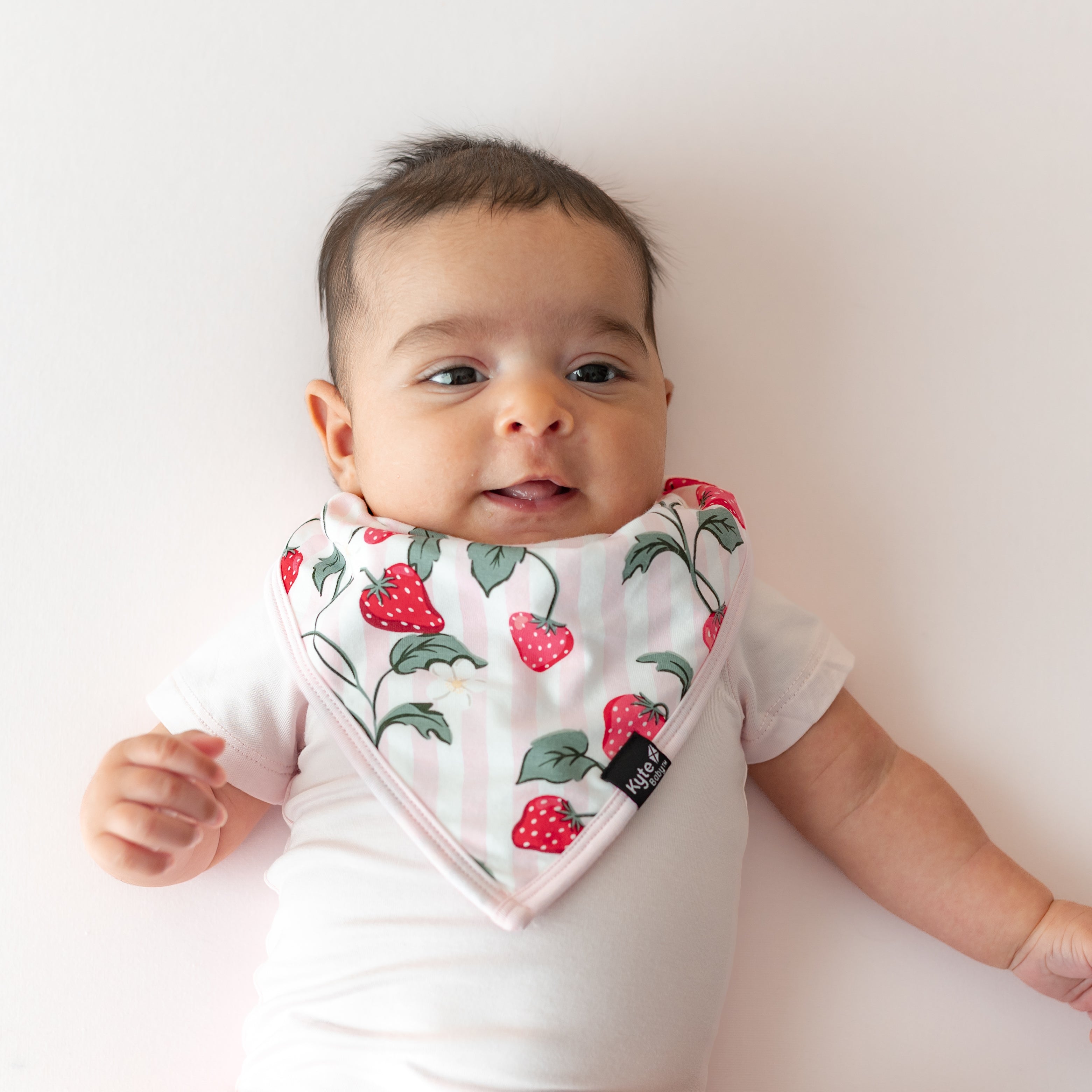 Close up of infant wearing the Bib in Strawberry Fields with a light pink short sleeve bodysuit