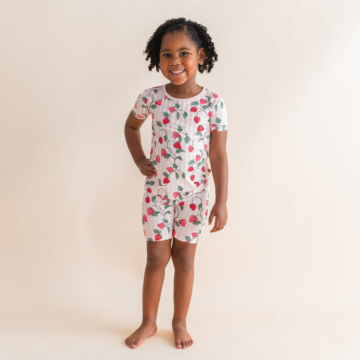 Young girl standing with hand on her hip in front of a light neutral background wearing the temperature regulating Short Sleeve Pajamas in Strawberry Fields