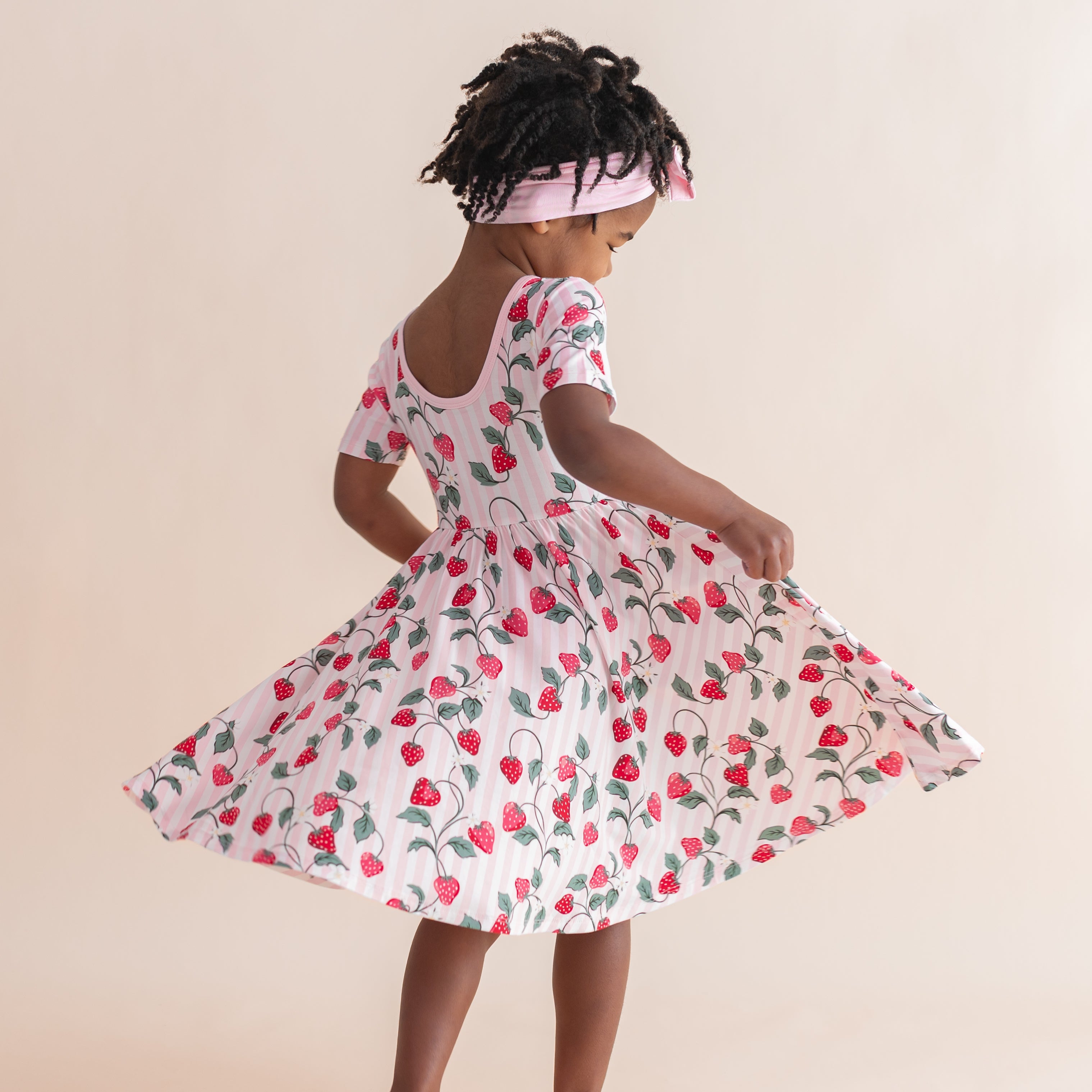The back of the Twirl Dress in Strawberry Fields shown on a young girl twirling