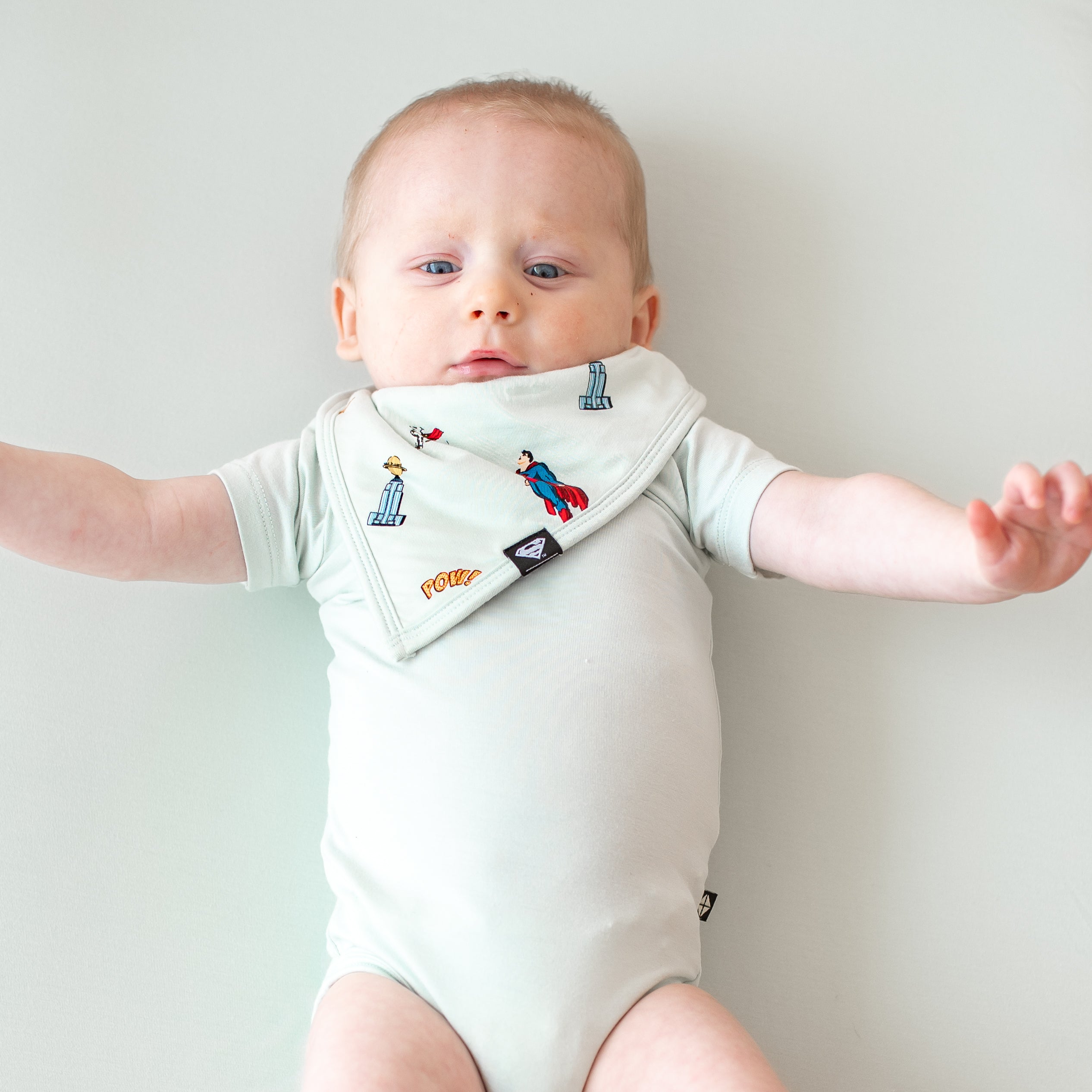 Infant wearing the Bib in Superman™ paired with a Dew Short Sleeve Bodysuit