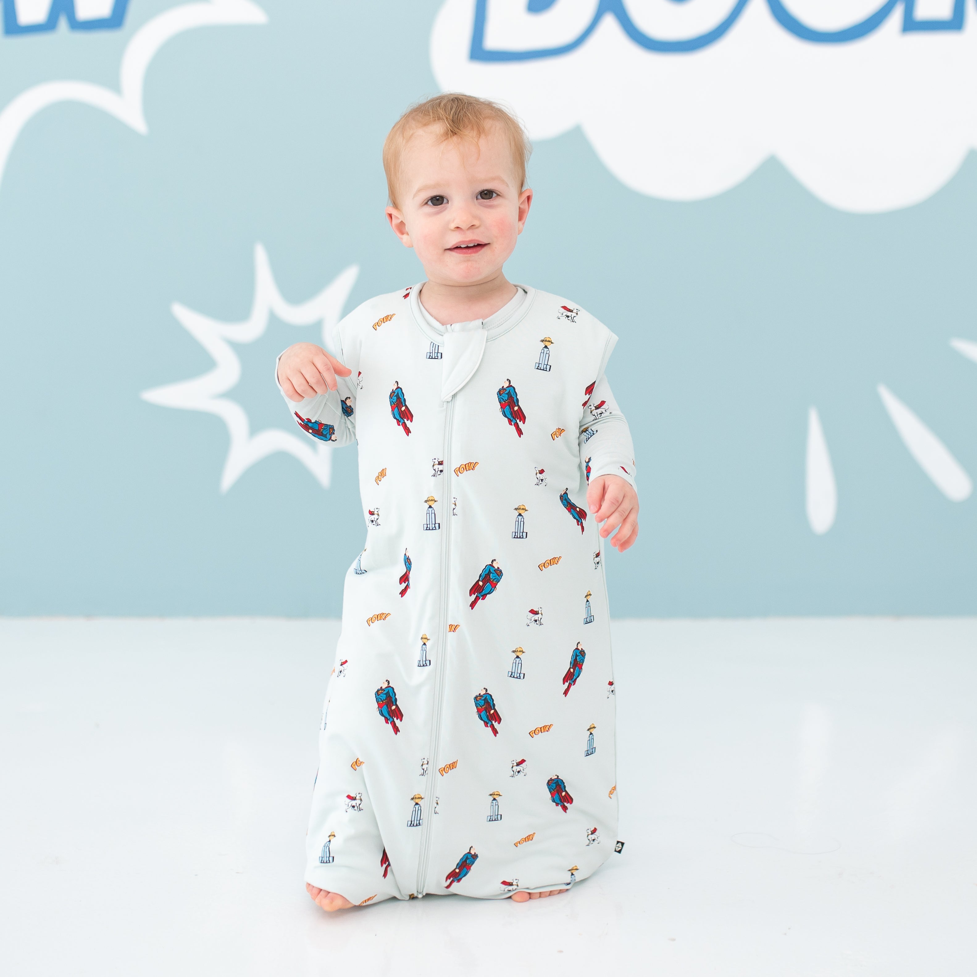 Toddler walking wearing the Sleep Bag Walker in Superman™ 1.0 paired with matching pajamas underneath