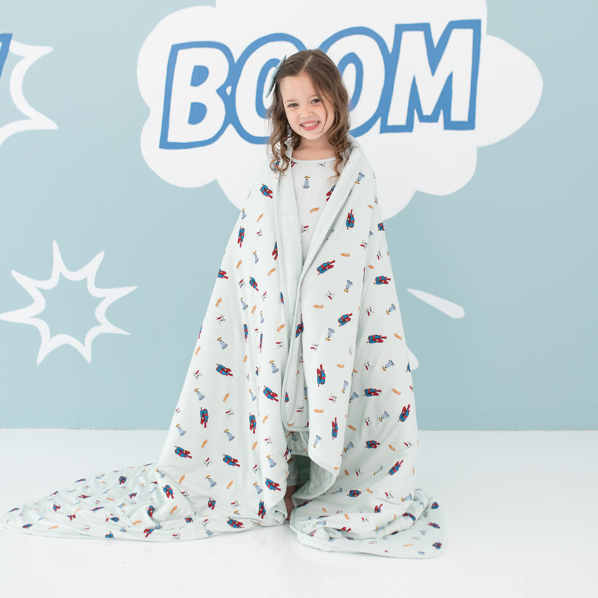 Smiling girl standing with the Youth Blanket in Superman™ 2.5 wrapped around her