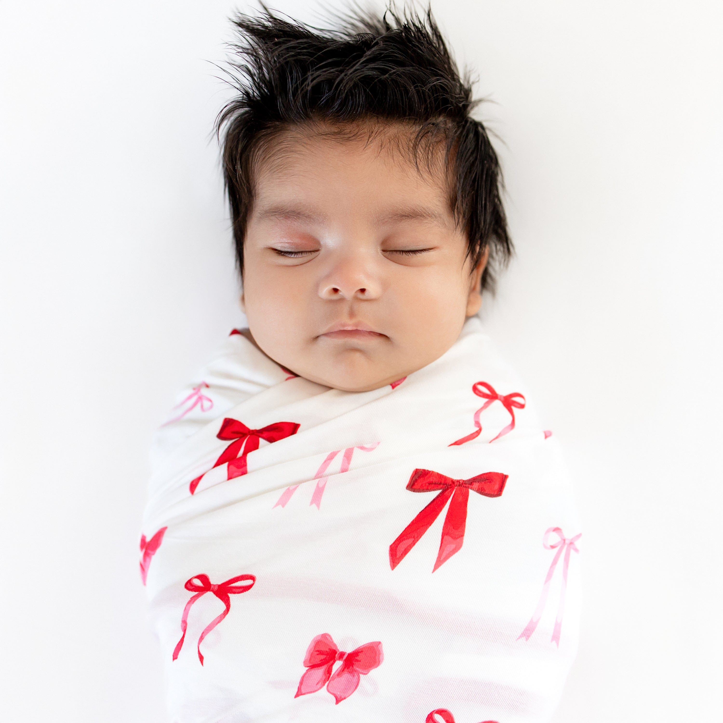 Close up of sleeping newborn swaddled in the Swaddle Blanket in Small Love Bow
