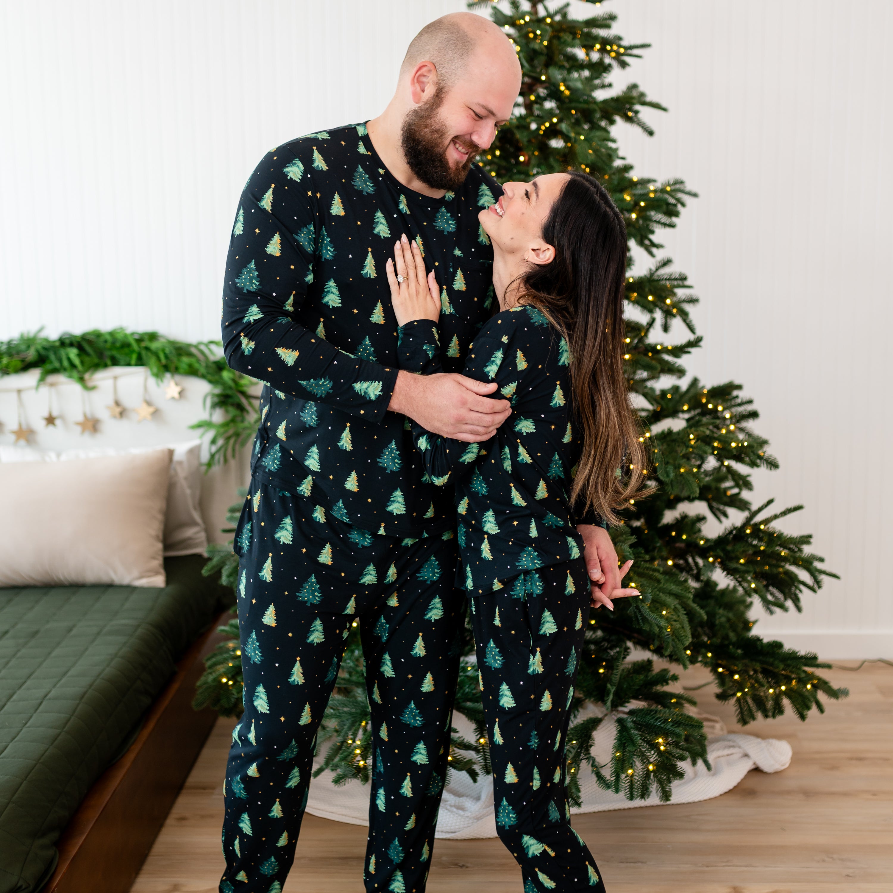 Wife standing with her husband with her hand on his chest both looking at one another matching in the Women's and Men's Jogger Pajama Set in Twinkle Tree