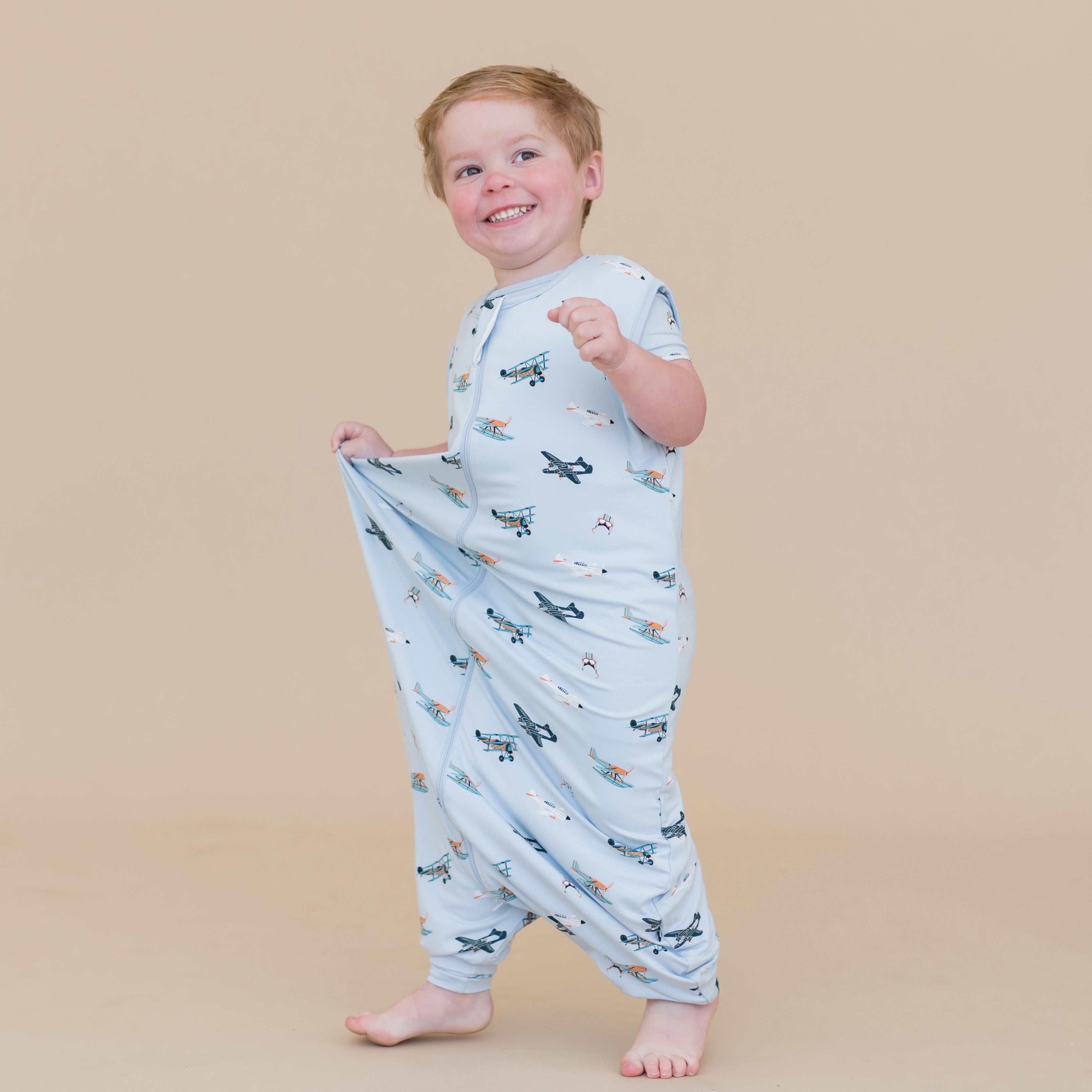 Young smiling boy walking wearing the Sleep Bag Walker in Take Off 0.5