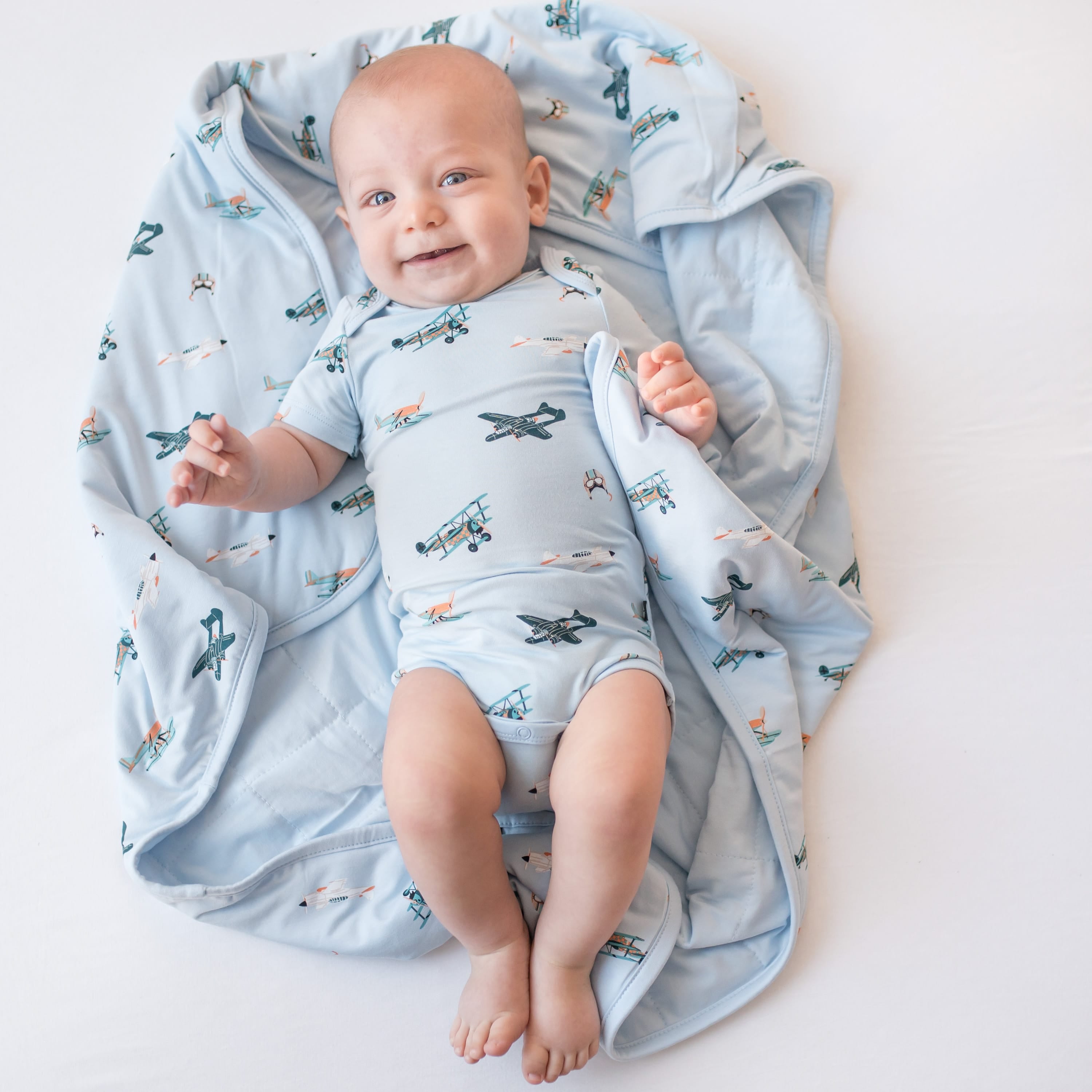 Young infant laying on a Baby Blanket in Take Off wearing a matching short sleeve bodysuit