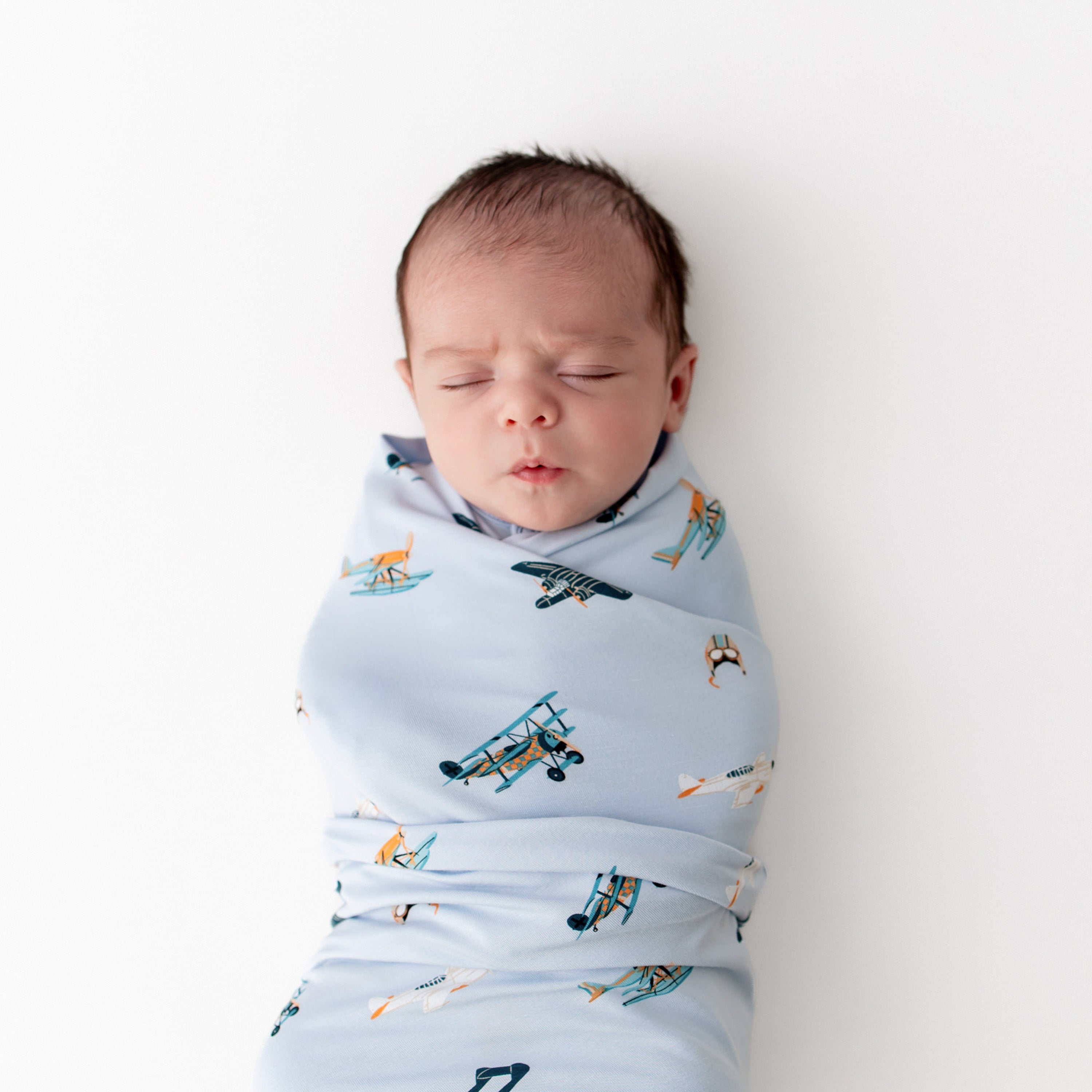 Close up of sleeping newborn wearing the Swaddle Blanket in Take Off