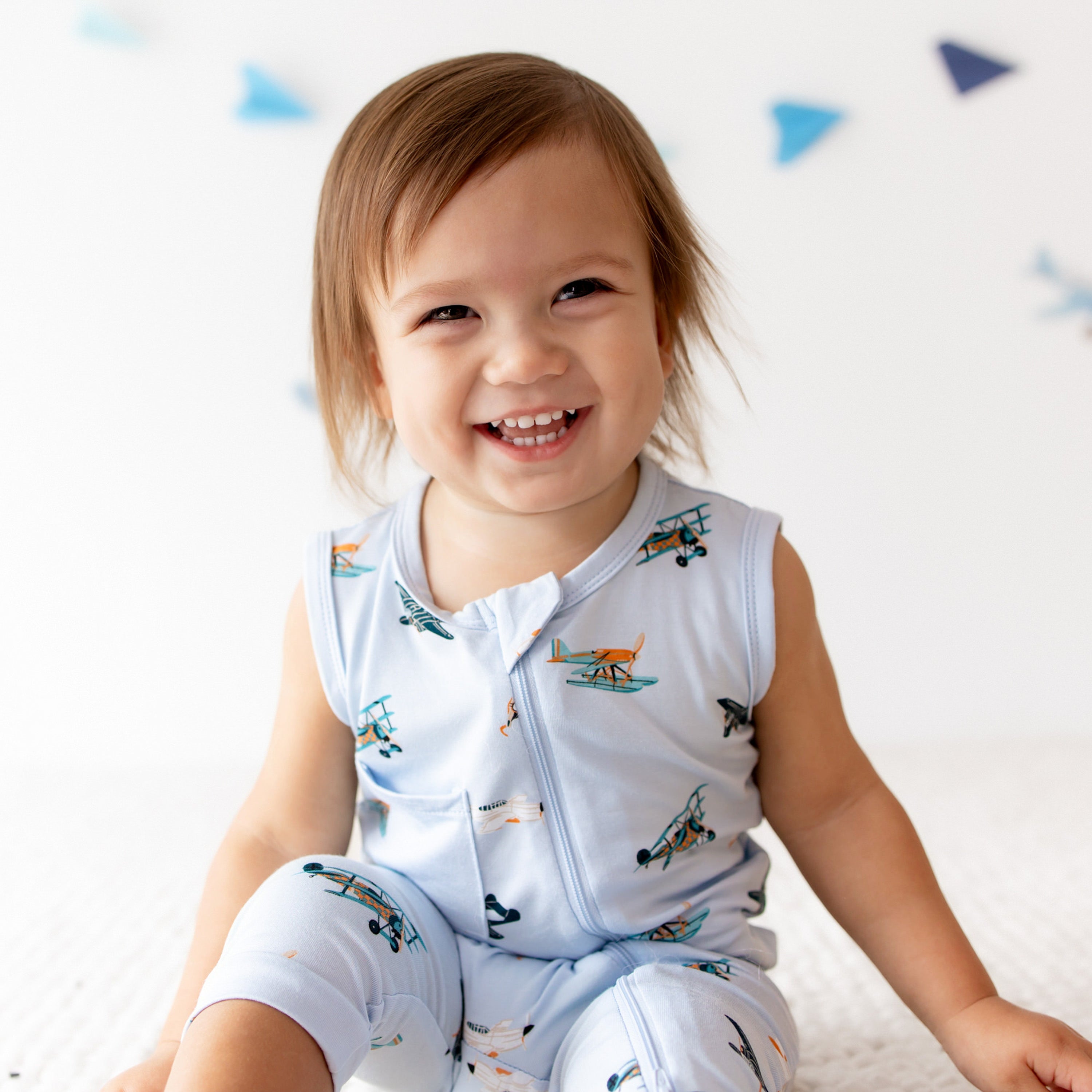 Close up of smiling toddler wearing the Zippered Sleeveless Romper in Take Off