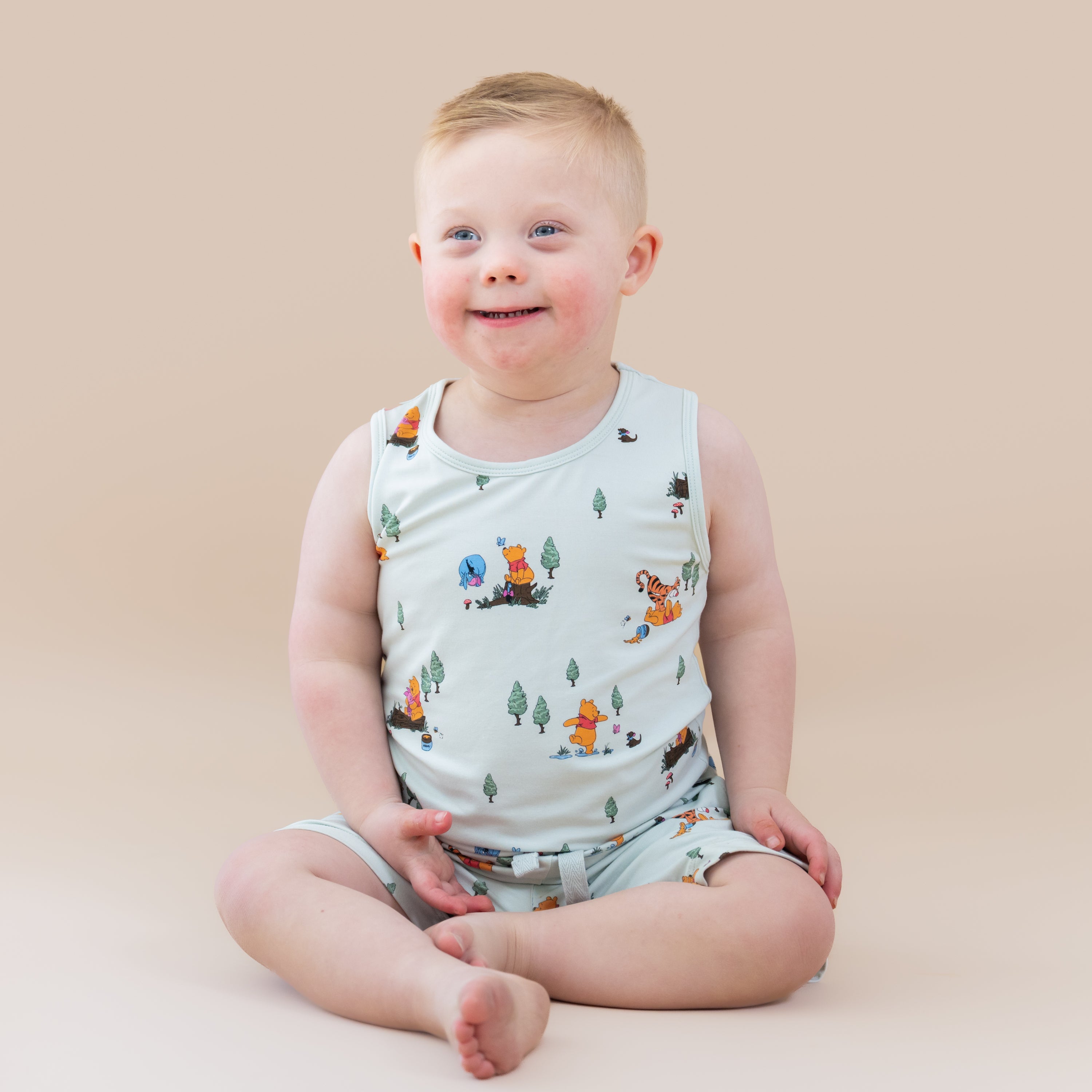 Young boy sitting on the floor wearing the Toddler Tank Top in Winnie the Pooh Hundred Acre Wood