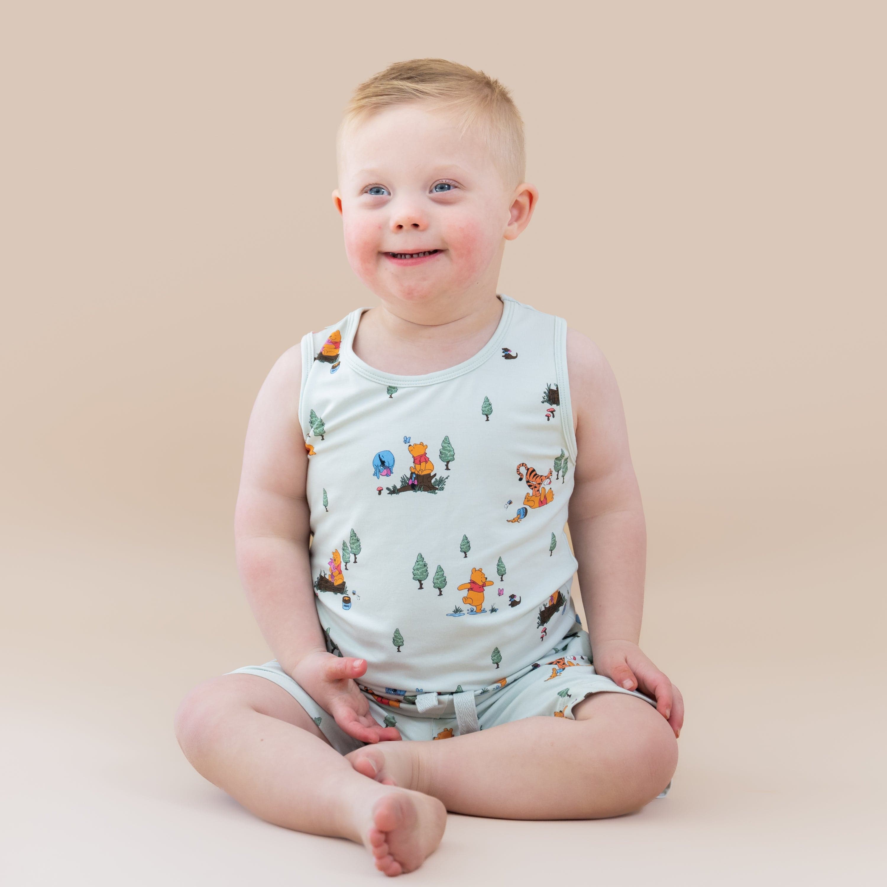Young boy sitting on the floor wearing the Toddler Tank Top in Winnie the Pooh Hundred Acre Wood