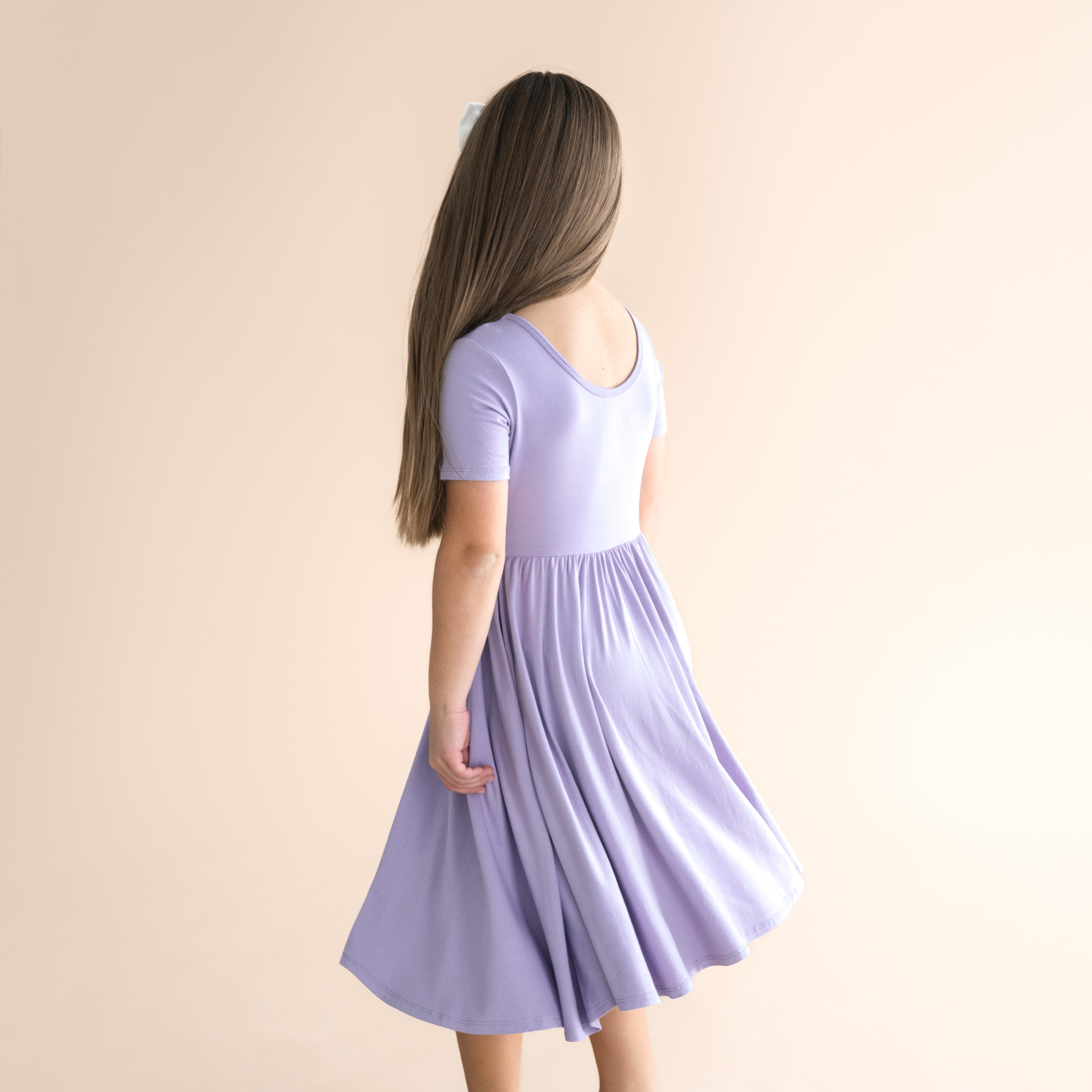Girl wearing a light purple dress against a beige background