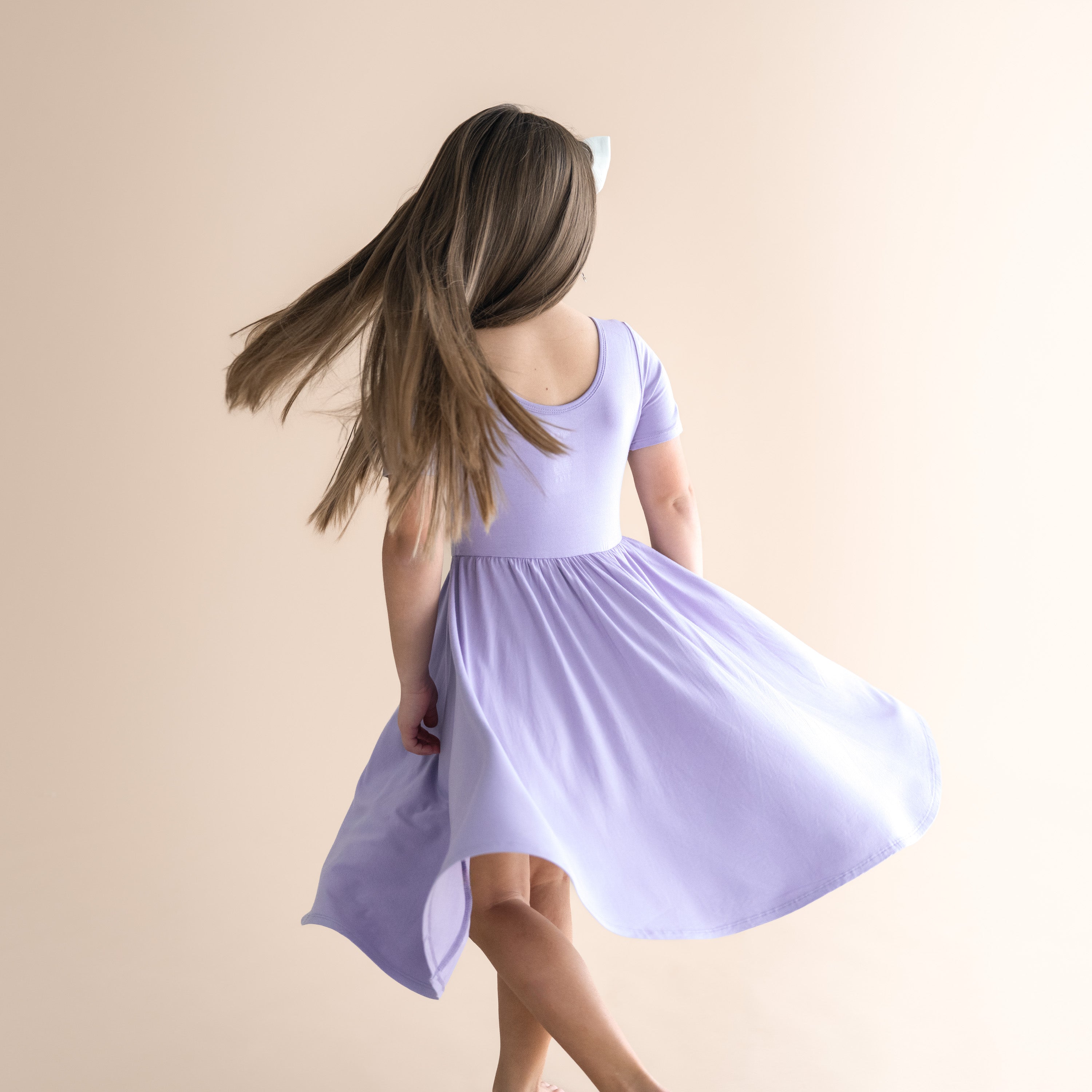 Girl wearing a light purple dress against a beige background
