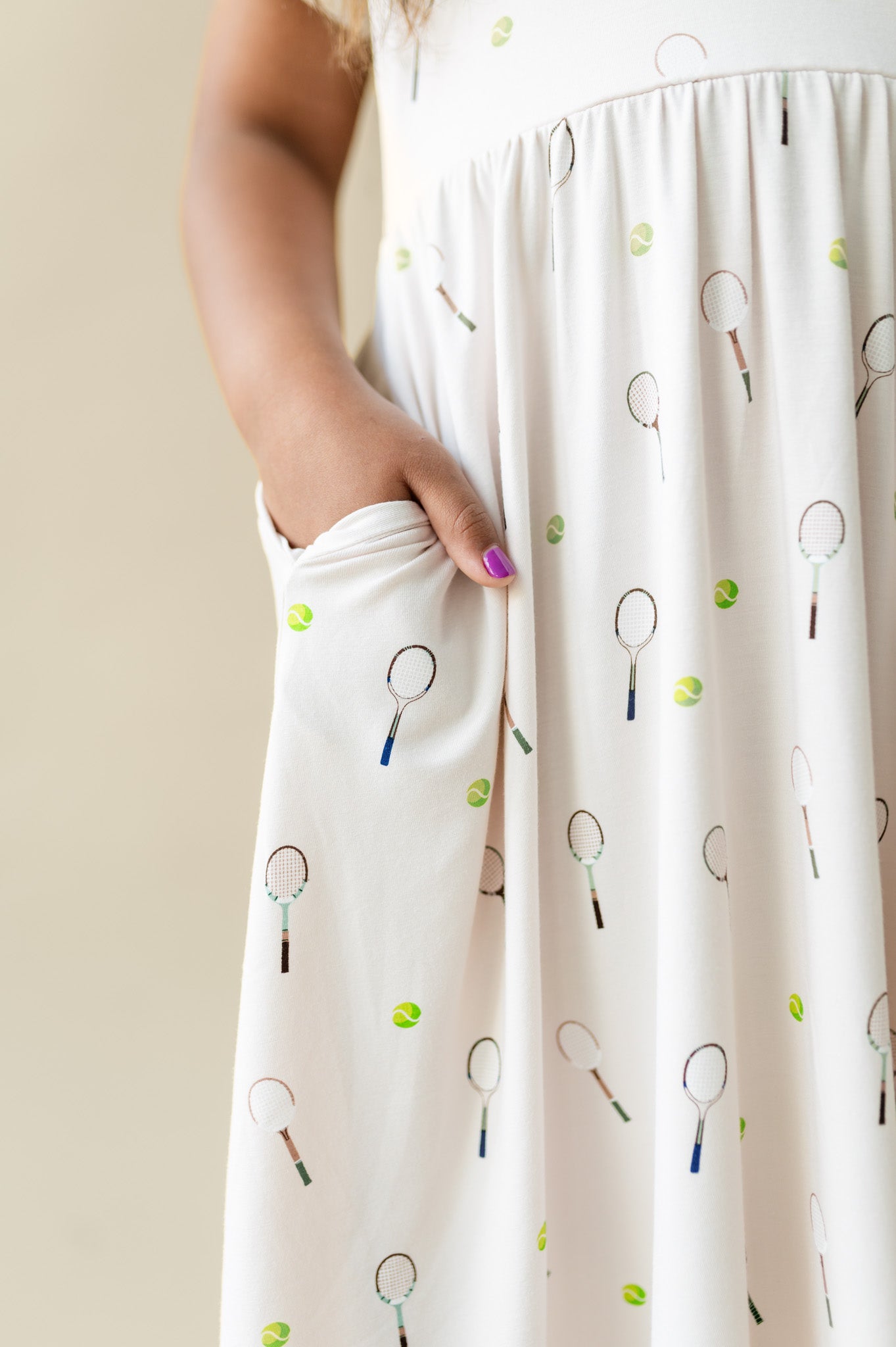 White dress with tennis racket and ball pattern worn by a person.