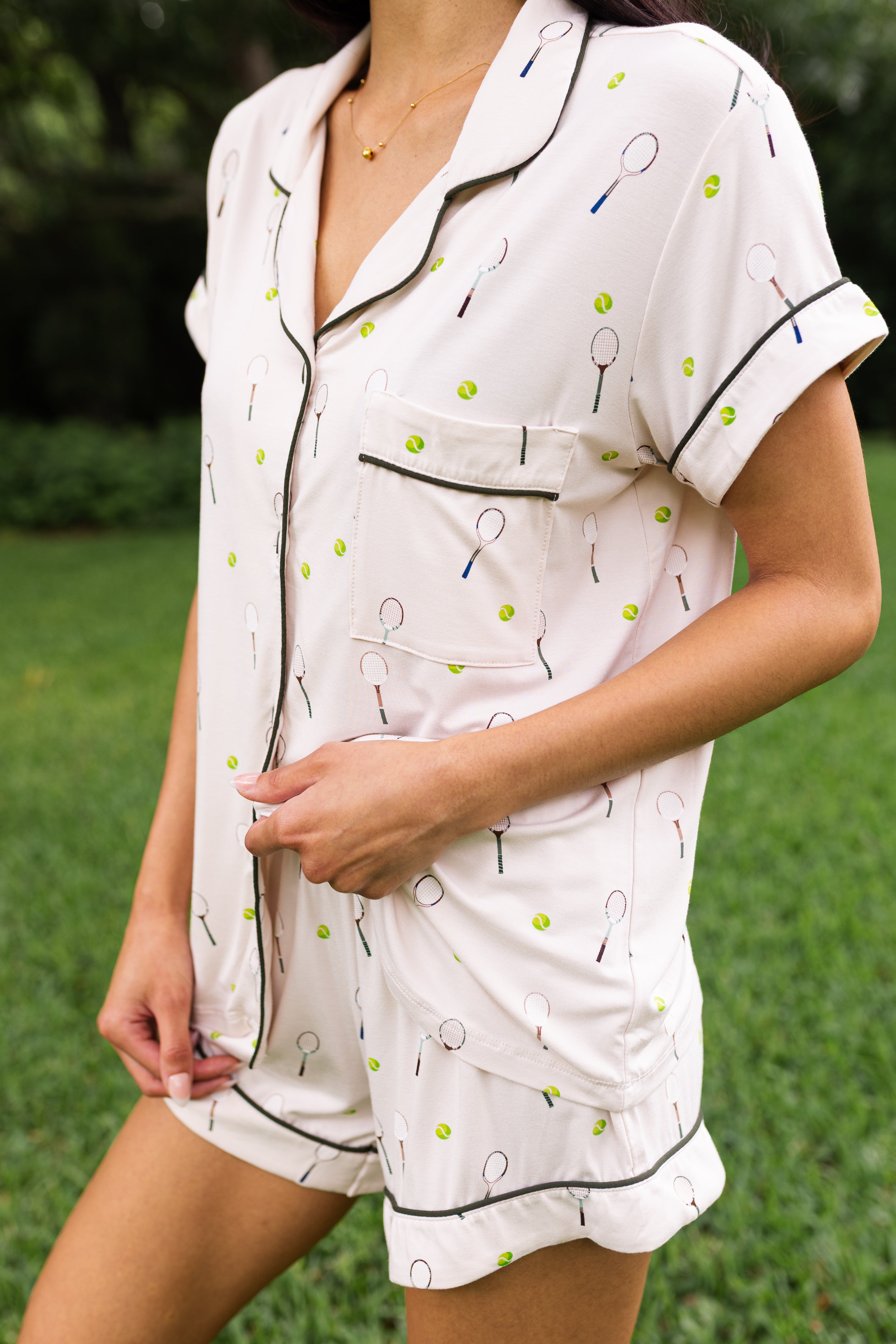Woman wearing short sleeve button up pajama set with tennis pattern outdoors